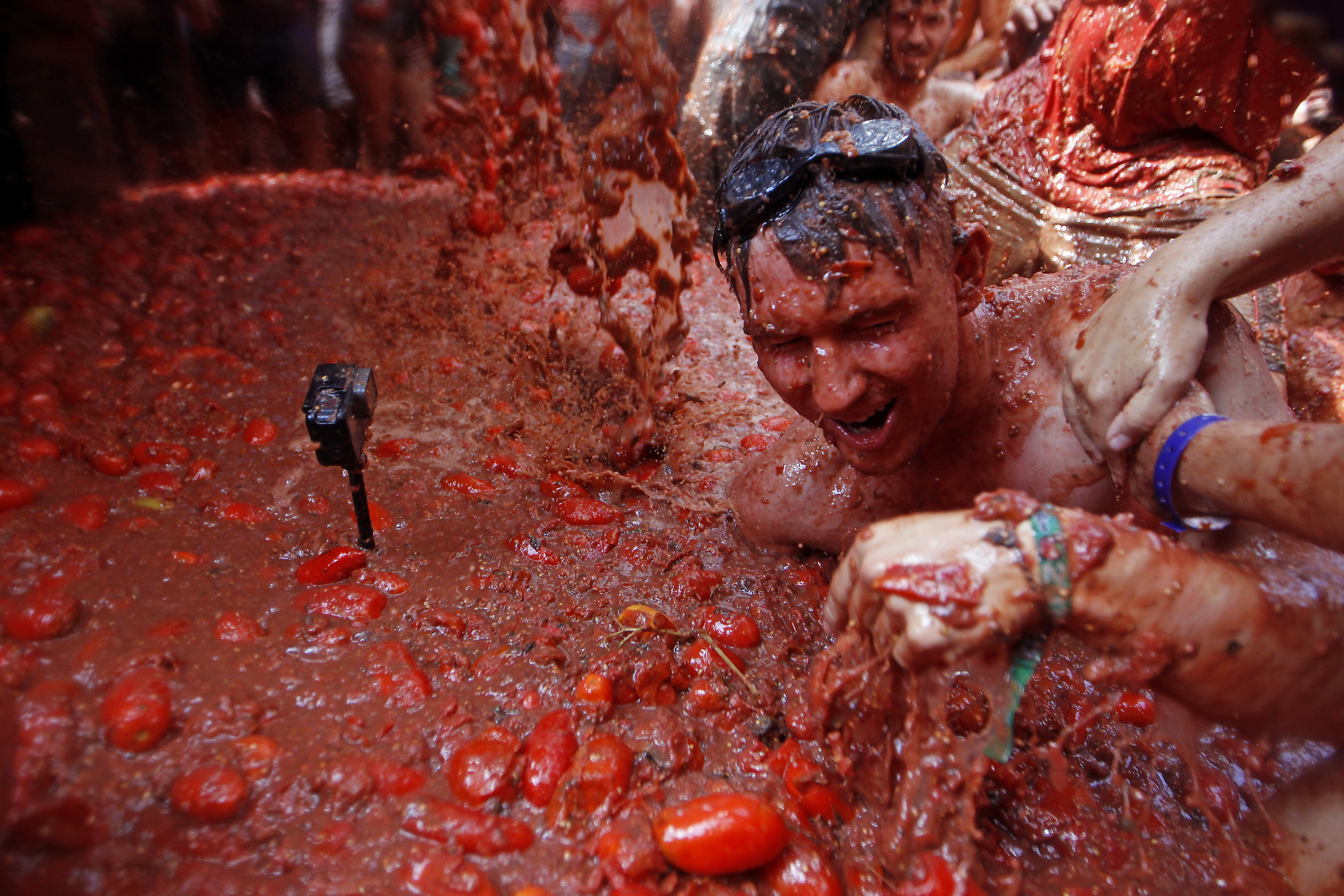A camera films revelers as they throw tomatoes at each other, during the annual 