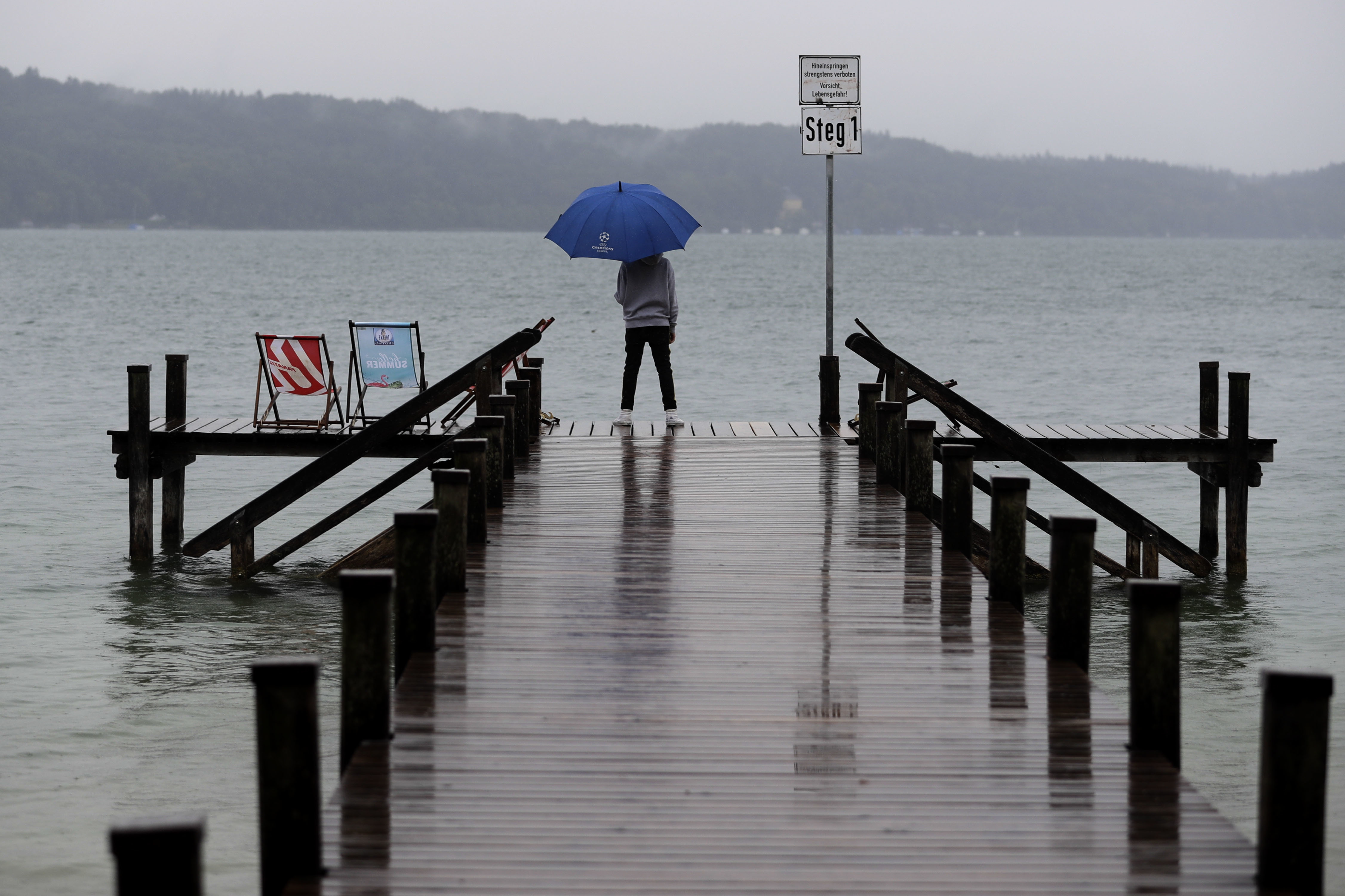 A young boy stands on a dock at the 'Starnberger See' lake in Starnberg, Germany, Friday, Aug. 31, 2018. (AP Photo/Matthias Schrader)