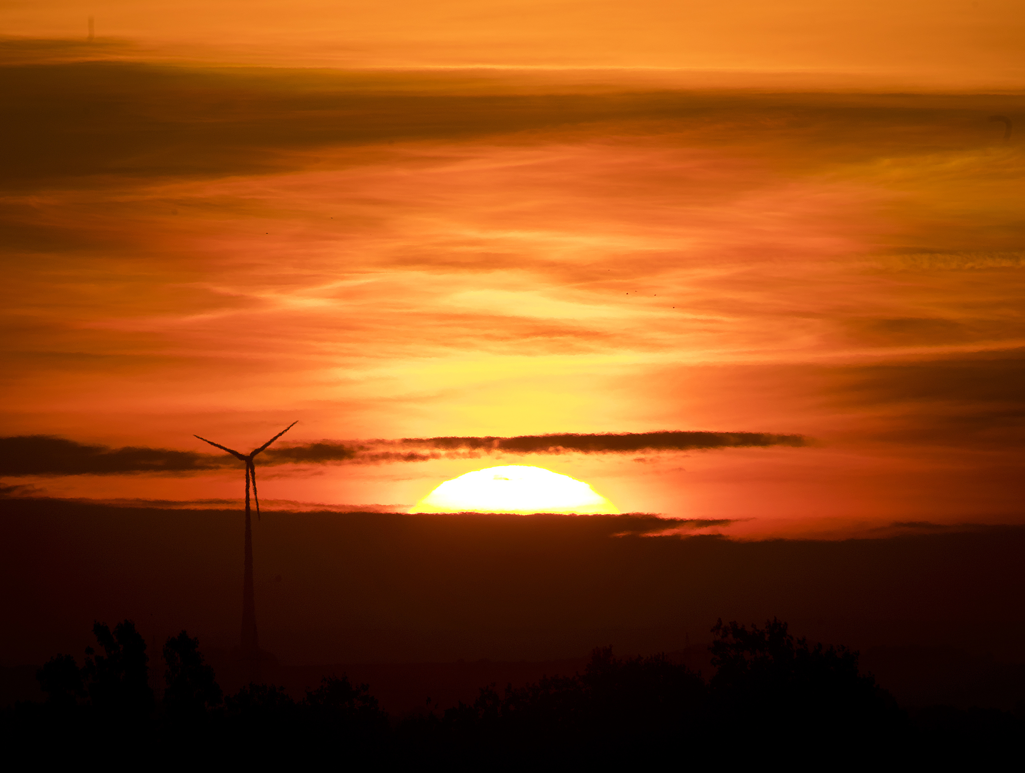 The sun rises near a wind power plant near Frankfurt, Germany, Tuesday, Sept. 11, 2018. (AP Photo/Michael Probst)