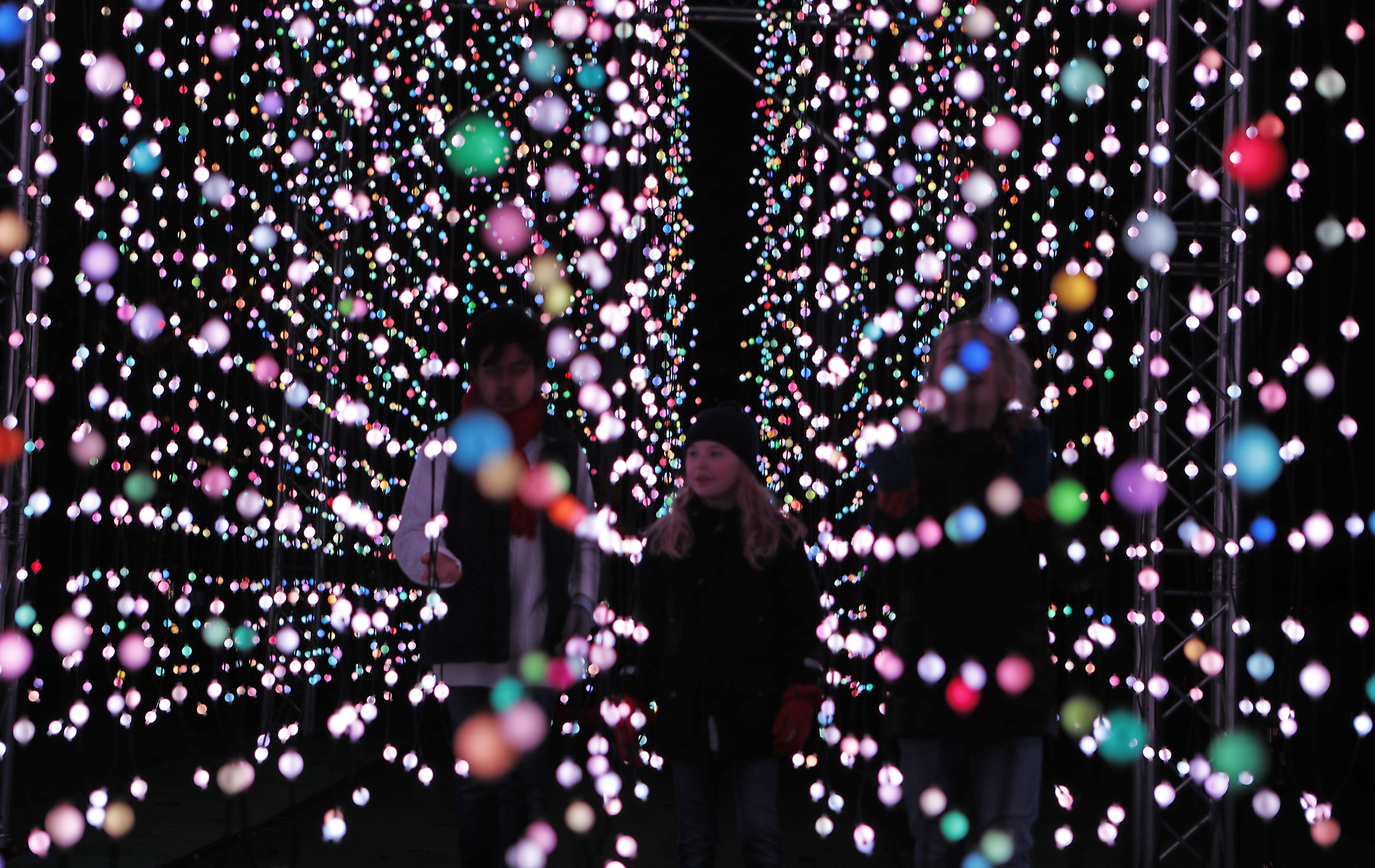 Visitors walk through the 'Feast of Light' part of the illuminated trail through Kew Gardens magnificent after-dark landscape, lit up by over one million twinkling lights in London, Wednesday, Nov. 21, 2018. The spectacular light and sound installations run from 22, November 2018 – 5, January 2019.(AP Photo/Frank Augstein)