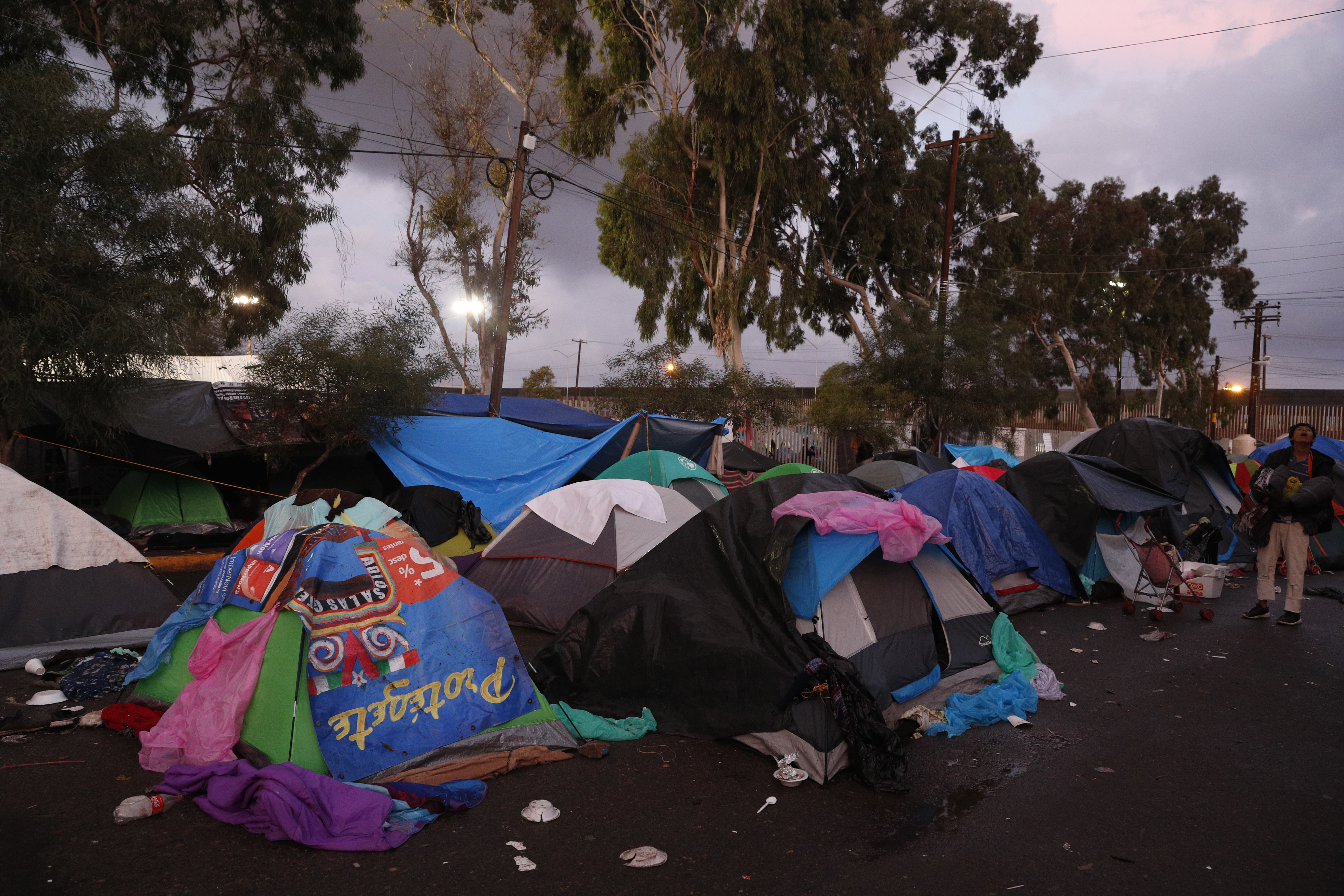 People sleep in tents on a wet street as dawn breaks, outside the Benito Juarez sports complex where thousands of migrants were camping out, in Tijuana, Mexico, Friday, Nov. 30, 2018. Authorities in the Mexican city of Tijuana have begun moving some of more than 6,000 Central American migrants from an overcrowded shelter on the border to an events hall further away.(AP Photo/Rebecca Blackwell)