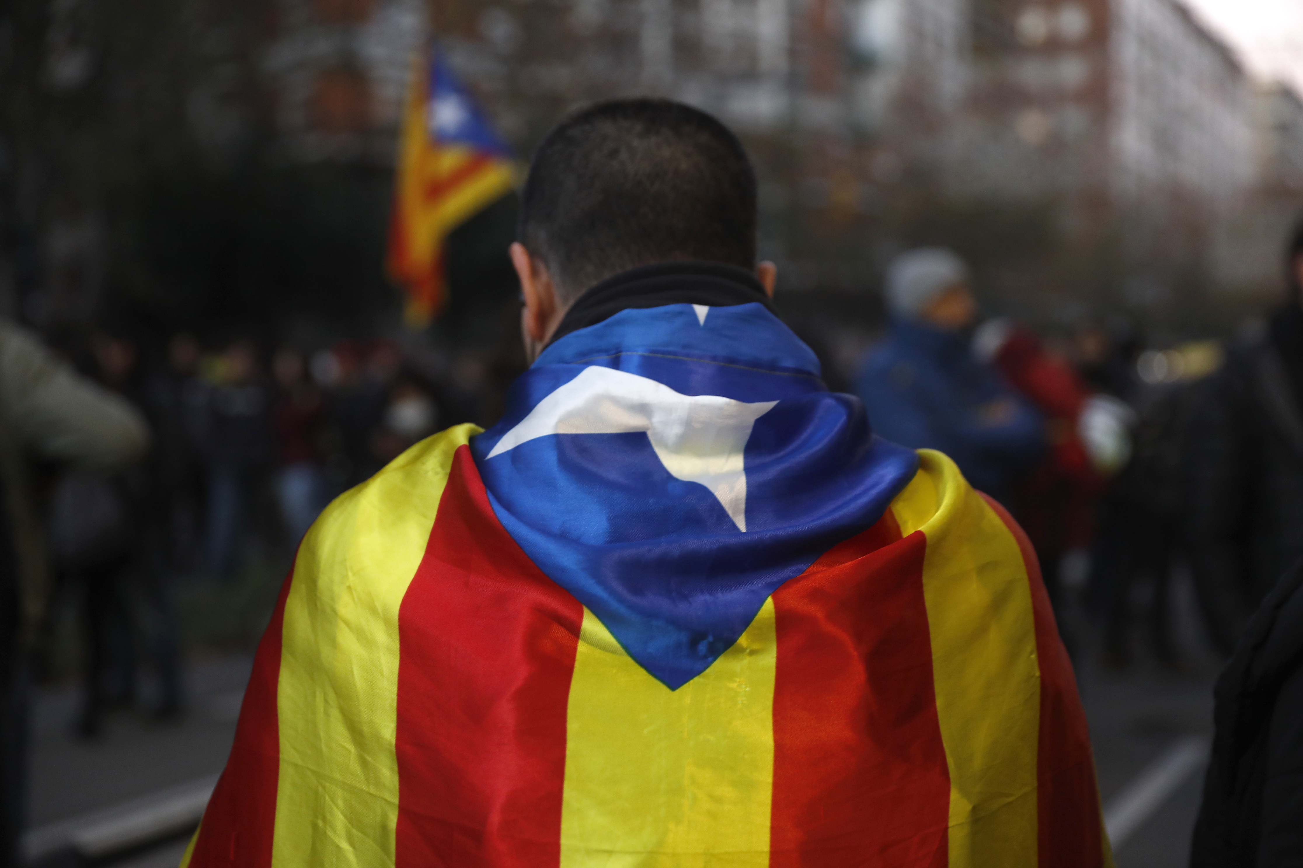 A pro-independence demonstrator stands in downtown Barcelona, Spain, Friday Dec. 21, 2018. Catalan authorities say pro-independence protesters angry about Spain's Cabinet holding a meeting in Barcelona have blocked a major highway and dozens of roads, disrupting traffic to and from the city.(AP Photo/Santi Palacios)