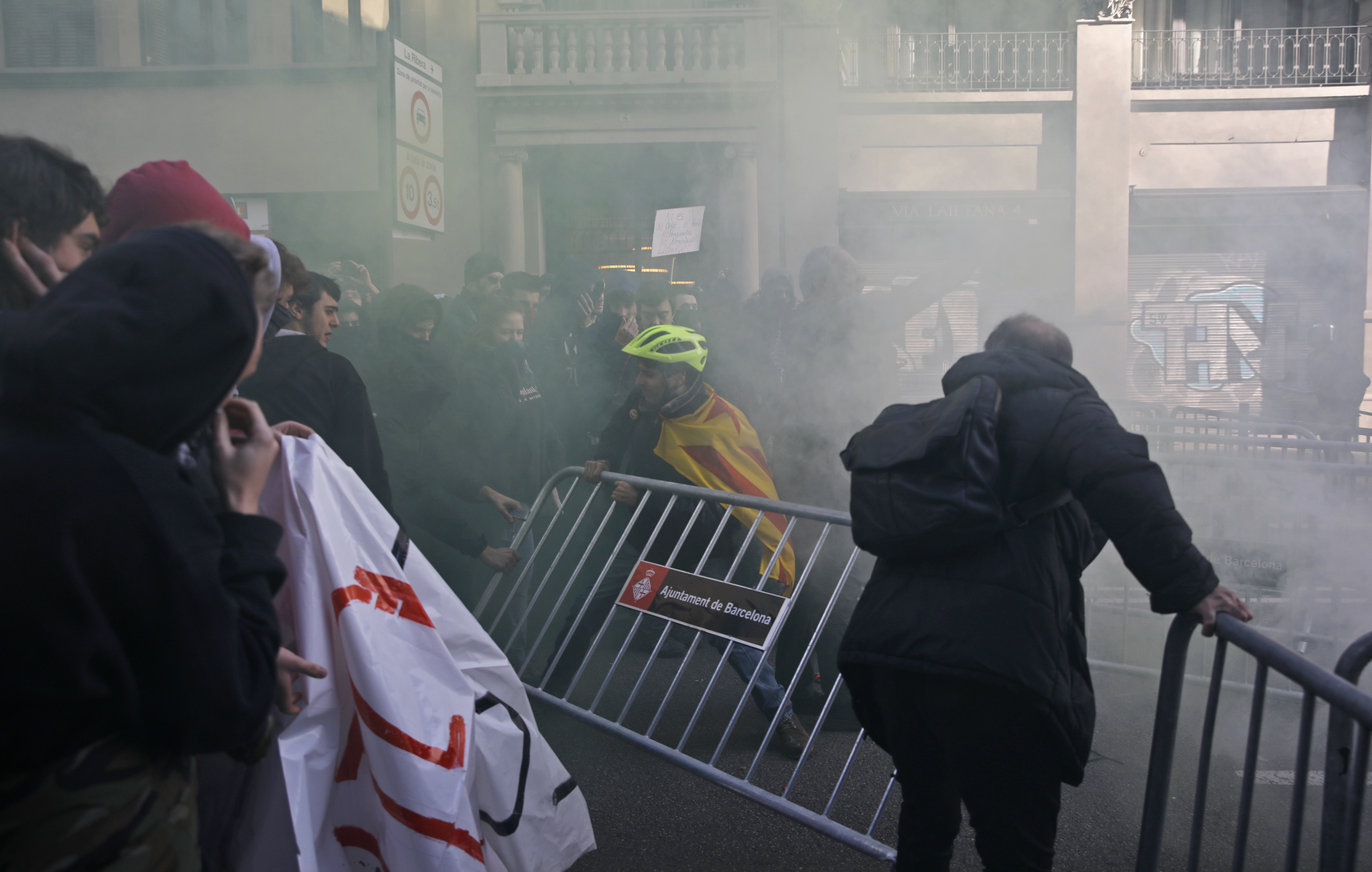 Engulfed by smoke caused by flares used by protesters, pro-independence demonstrators remove a fence blocking access to the area where Spain's cabinet is holding a meeting in Barcelona Spain, Friday Dec. 21, 2018. Some scuffles have broken out between protesters trying to reach the venue of the cabinet meeting and police trying to stop them on Friday in central Barcelona after pro-independence organizations called for peaceful demonstrations against the meeting across the city.(AP Photo/Emilio Morenatti)