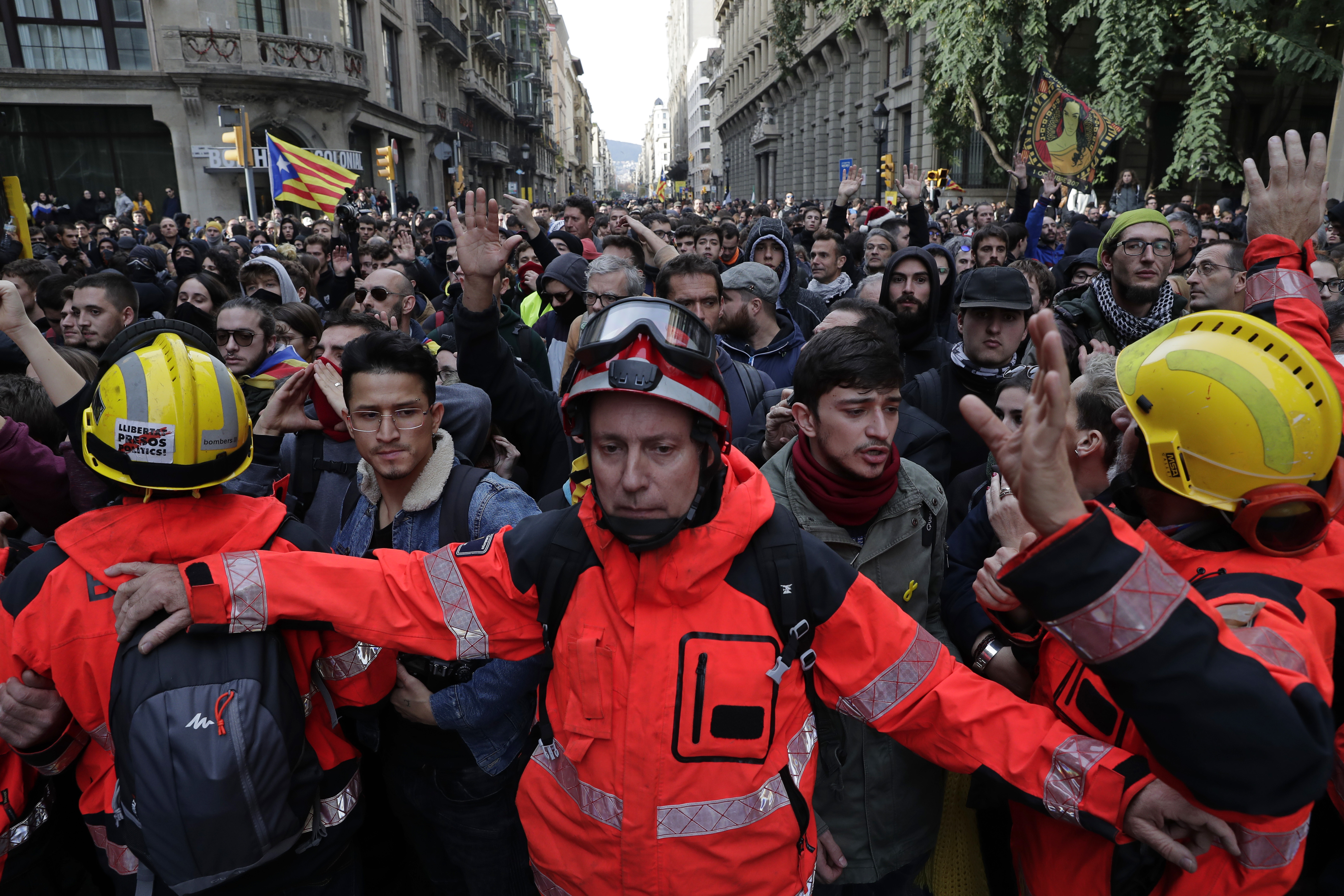 Firefighters help to control the demonstrators during a protest against Spain's cabinet holding a meeting in Barcelona Spain, Friday Dec. 21, 2018. Scuffles broke out between protesters trying to reach the venue of the cabinet meeting and police trying to stop them on Friday in central Barcelona after pro-independence organizations called for peaceful demonstrations against the meeting across the city. (AP Photo/Manu Fernandez)