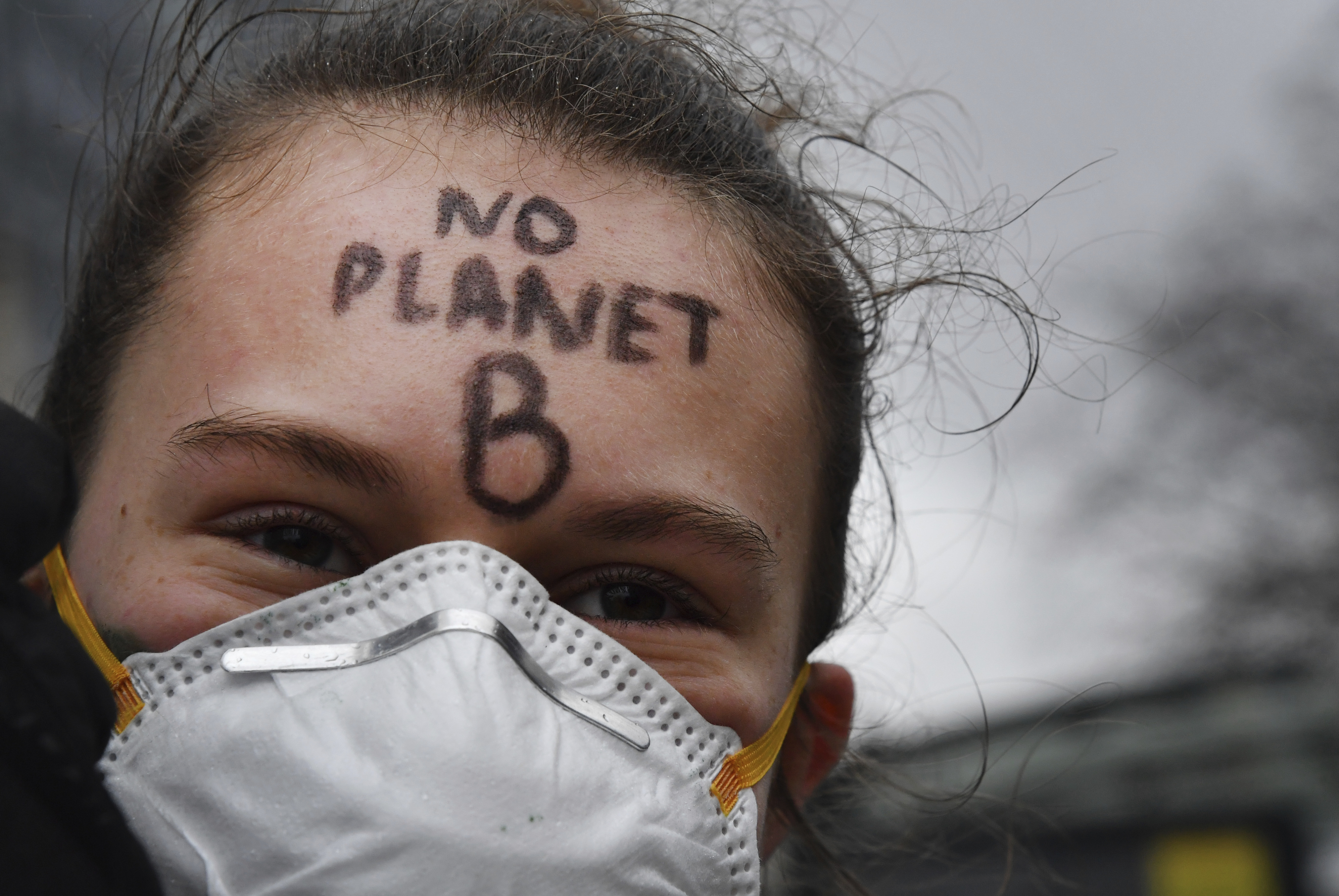 A protestor marches with a face mask and a message on her forehead during a Rise for the Climate demonstration in Brussels, Sunday, Jan. 27, 2019. (AP Photo/Geert Vanden Wijngaert)