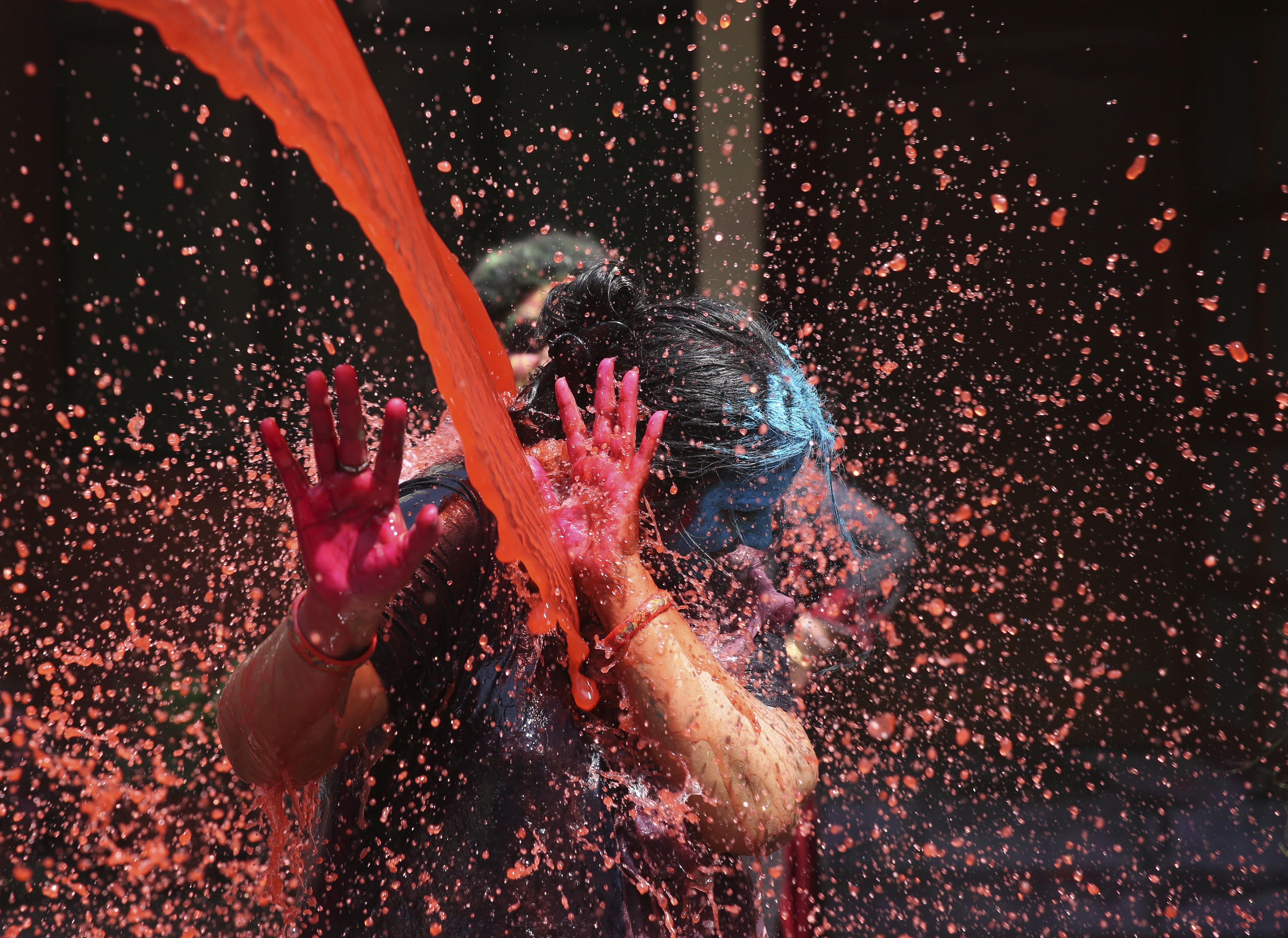 Colored water is splashed on a woman during Holi festivities in Allahabad, India, Thursday, March 21, 2019. This exuberant festival originally held to celebrate the fertility of the land, is also associated with the immortal love of Hindu God Krishna and Radha. Holi celebration is an excuse for Indians to shed inhibitions for a day of spring fever and big fun. (AP Photo/Rajesh Kumar Singh)