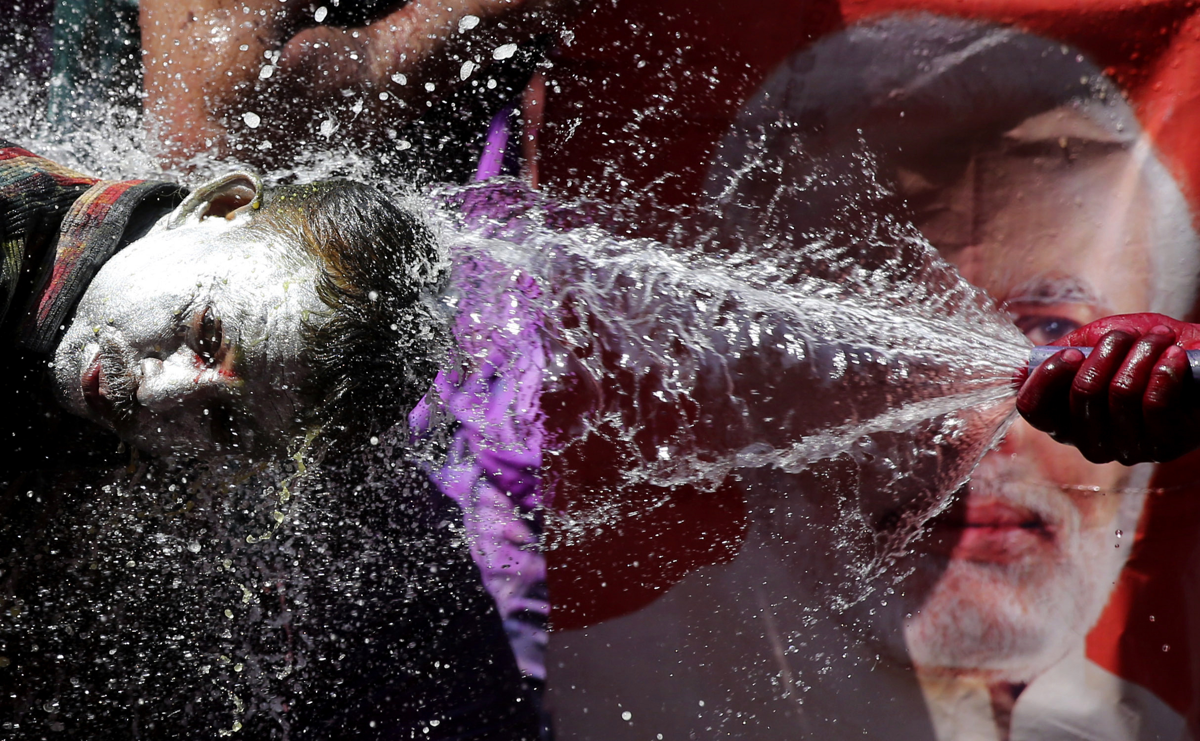 An Indian reveler has water sprayed on his head during celebrations to mark Holi, the Hindu festival of colors, in Prayagraj, India, Friday, March 22, 2019. Indians on Thursday celebrated Holi, the riotous annual celebration of color, that marks the end of winter and the arrival of spring. People armed with water balloons, colored water and powder in multiple hues played Holi by smearing each other's faces with color. (AP Photo/Rajesh Kumar Singh)
