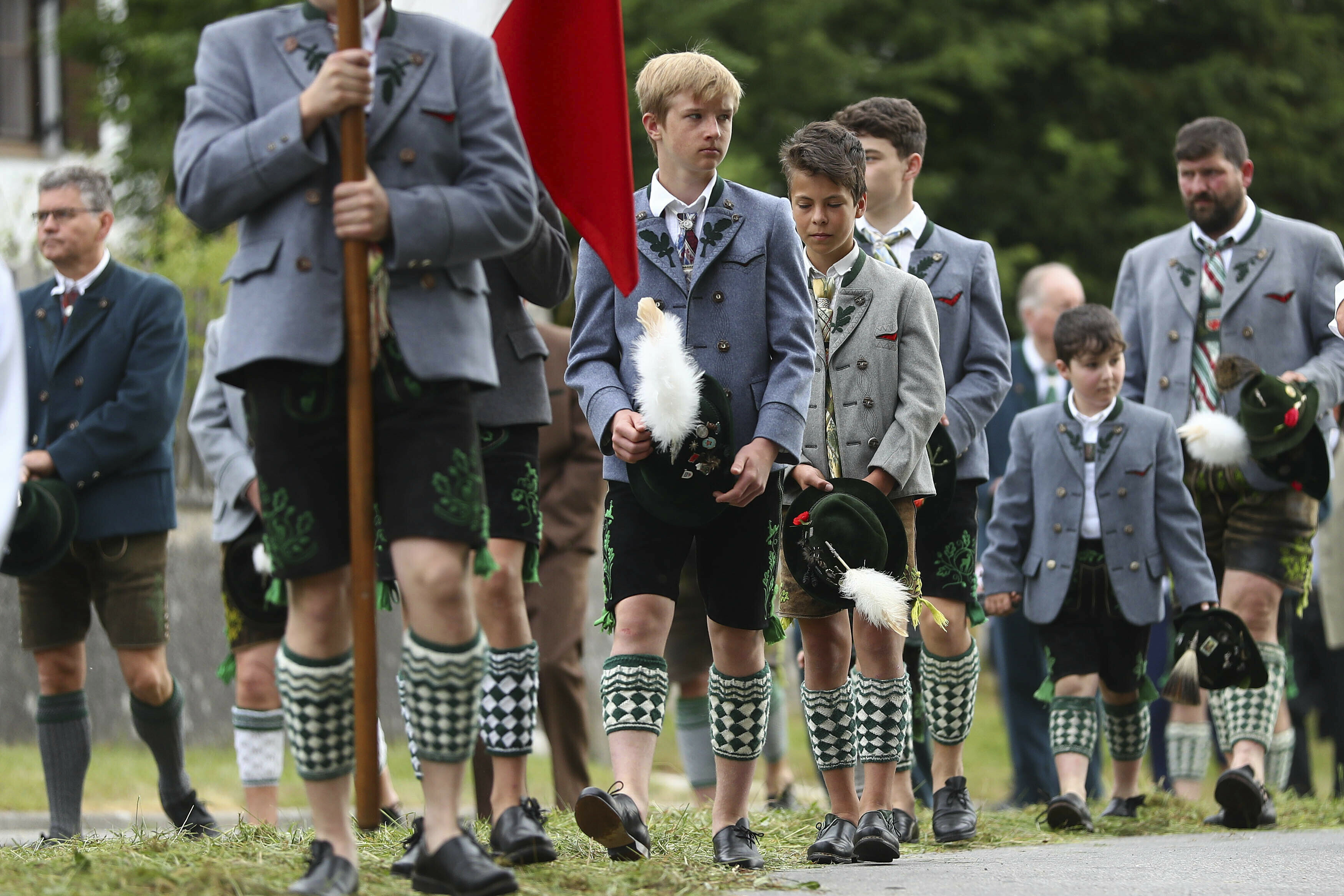 Young boys dressed in traditional clothes wait for the start of a Corpus Christi procession at lake Staffelsee in Seehausen near Murnau, Germany, Thursday, June 20, 2019. (AP Photo/Matthias Schrader)