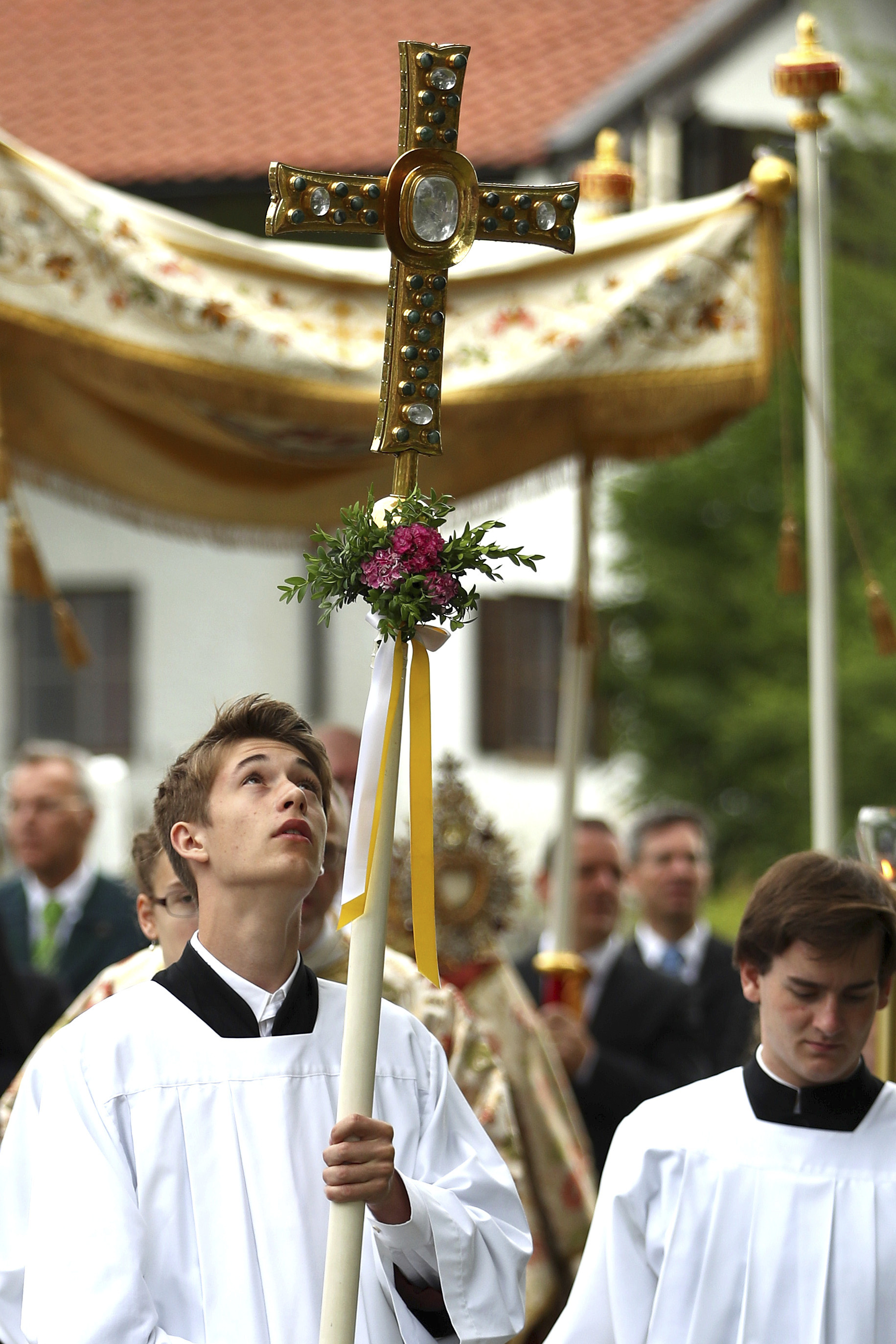 A young man carries a cross during a Corpus Christi procession at lake Staffelsee in Seehausen near Murnau, Germany, Thursday, June 20, 2019. (AP Photo/Matthias Schrader)