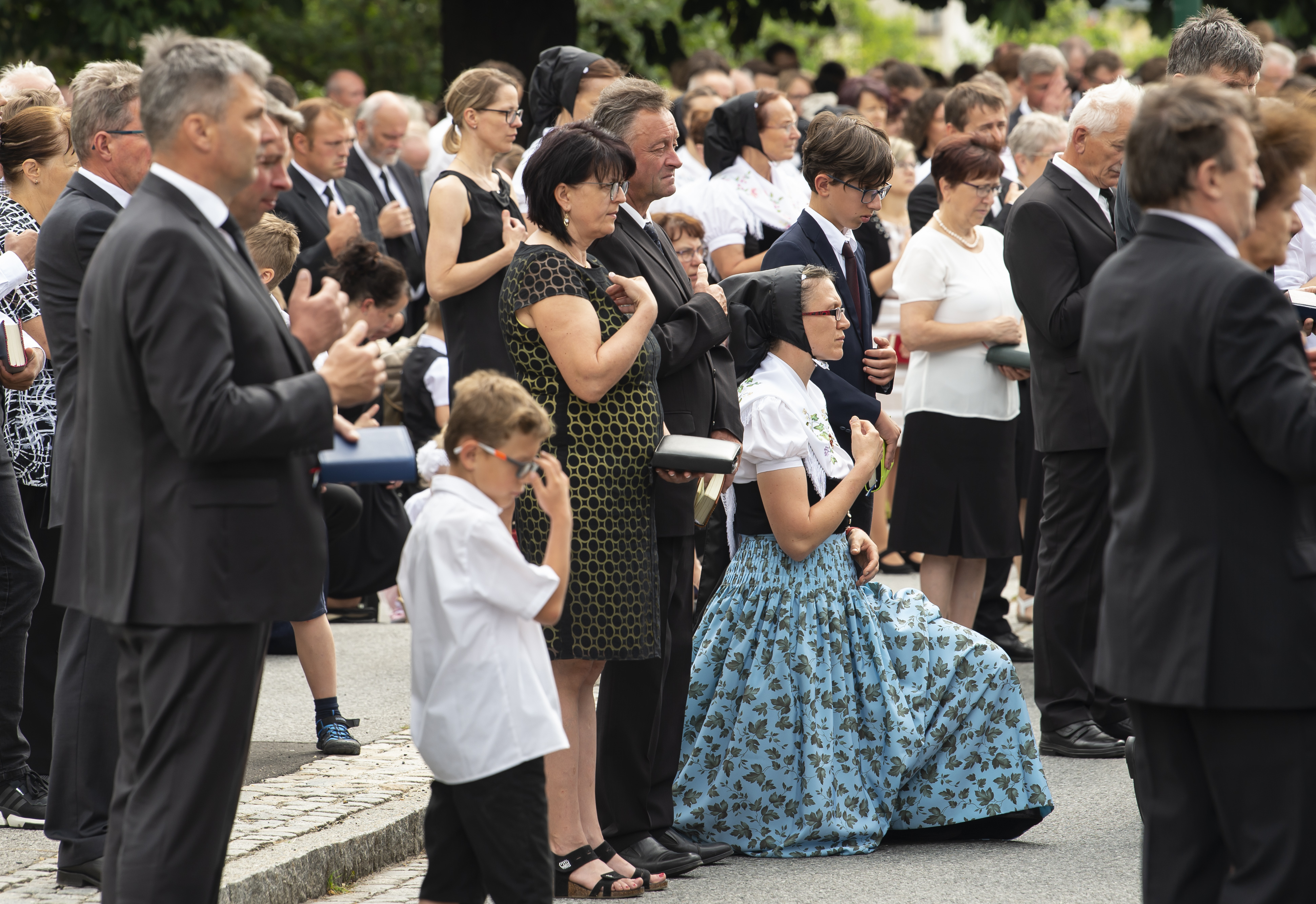 People dressed in the traditional clothes cross themselves during a Corpus Christi procession in Crostwitz, Germany, Thursday, June 20, 2019. The catholic faithful Sorbs are acknowledged as a national minority near the German-Polish border with their own language in eastern Germany. The procession to commemorate the solemnity of the body and blood of Christ has been a tradition in Lusatia (Lausitz) region. (AP Photo/Jens Meyer)