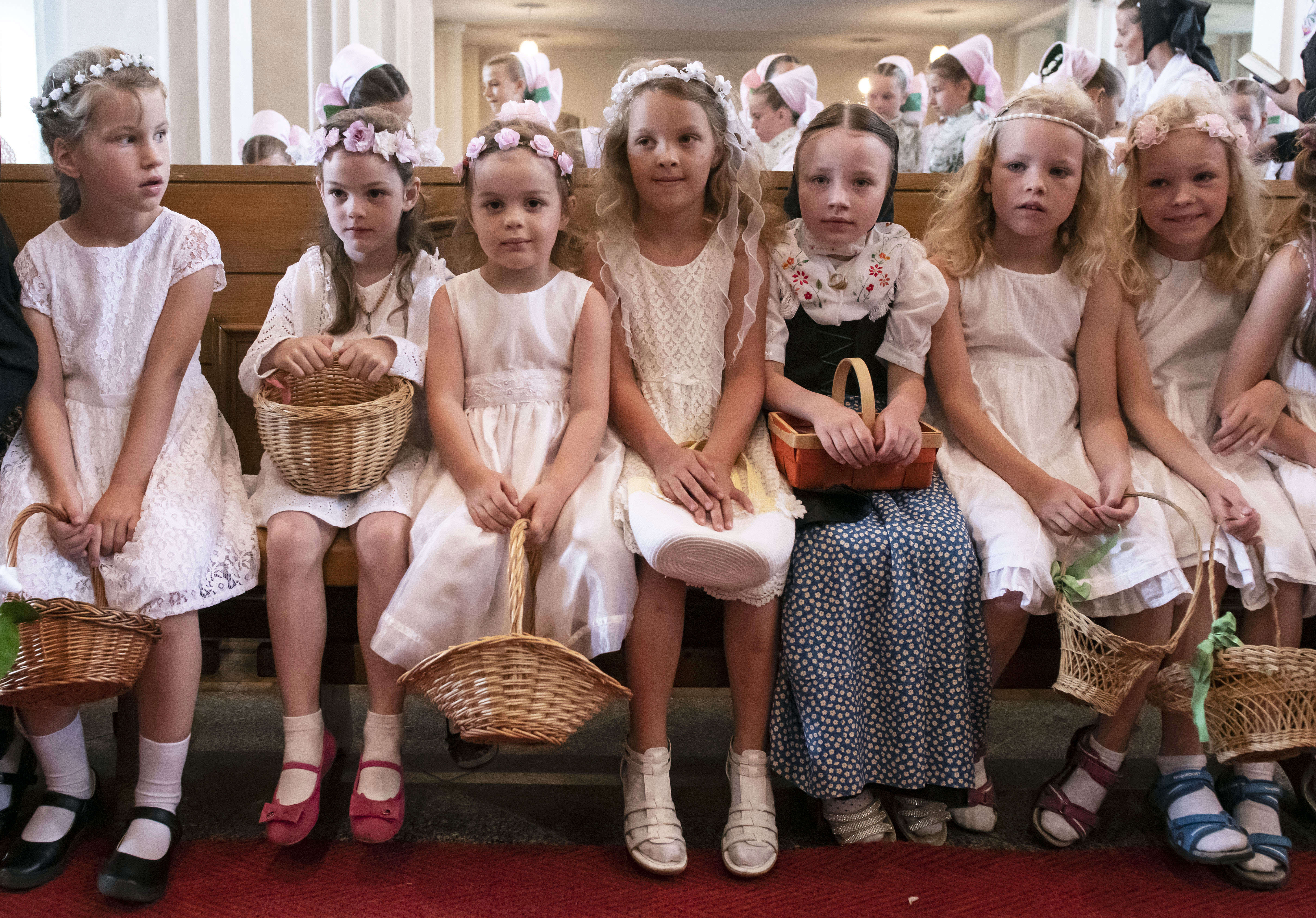 Children dressed in the traditional clothes of the Sorbs attend a holy mass during a Corpus Christi procession in Crostwitz, Germany, Thursday, June 20, 2019. The catholic faithful Sorbs are acknowledged as a national minority near the German-Polish border with their own language in eastern Germany. The procession to commemorate the solemnity of the body and blood of Christ has been a tradition in Lusatia (Lausitz) region. (AP Photo/Jens Meyer)