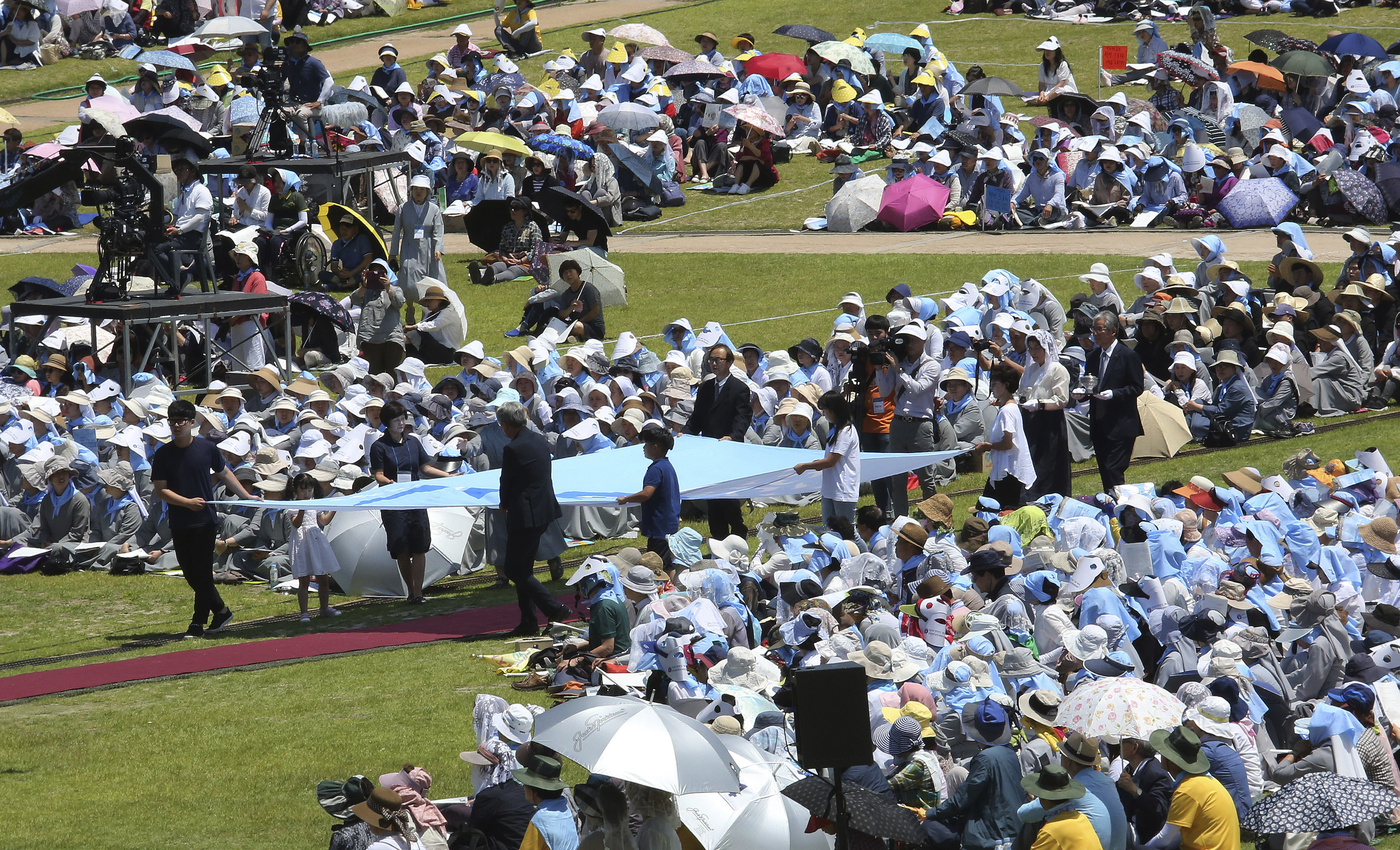 South Korean Catholic believers carry a unification flag during a service to mark the 69th anniversary of the outbreak of the Korean War at the Imjingak Pavilion, near the demilitarized zone of Panmunjom, in Paju, South Korea, Tuesday, June 25, 2019. South Korea and North Korea fought a devastating three-year war in the early 1950s that ended with an armistice, not a peace treaty. (AP Photo/Ahn Young-joon)