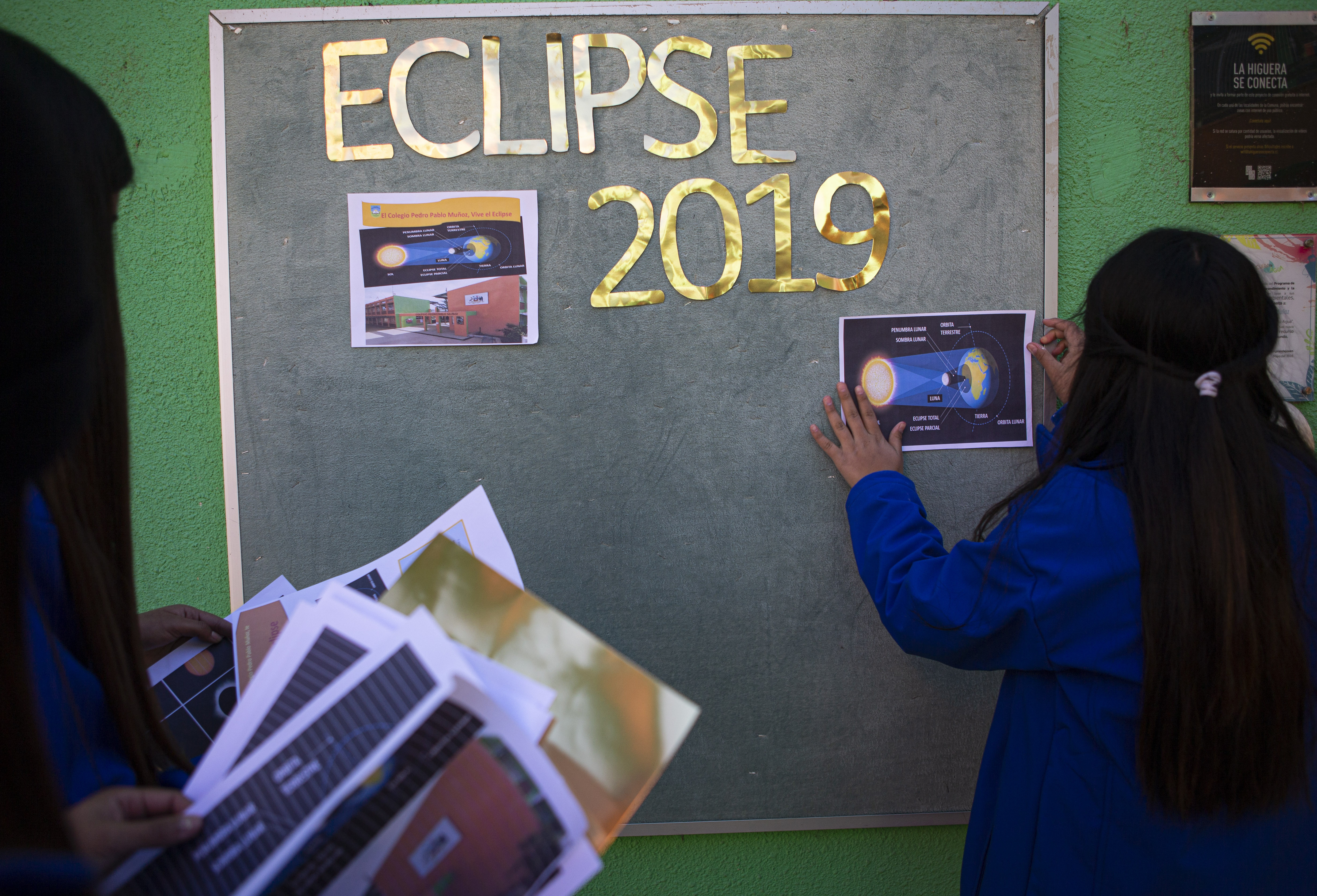 Students decorate a wall about the next day's total solar eclipse at their school in La Higuera, Chile, Monday, July 1, 2019. Tourists and scientists will gather in northern Chile, one of the best places in the world to watch the next the eclipse that will plunge parts of South America into darkness. (AP Photo/Esteban Felix)
