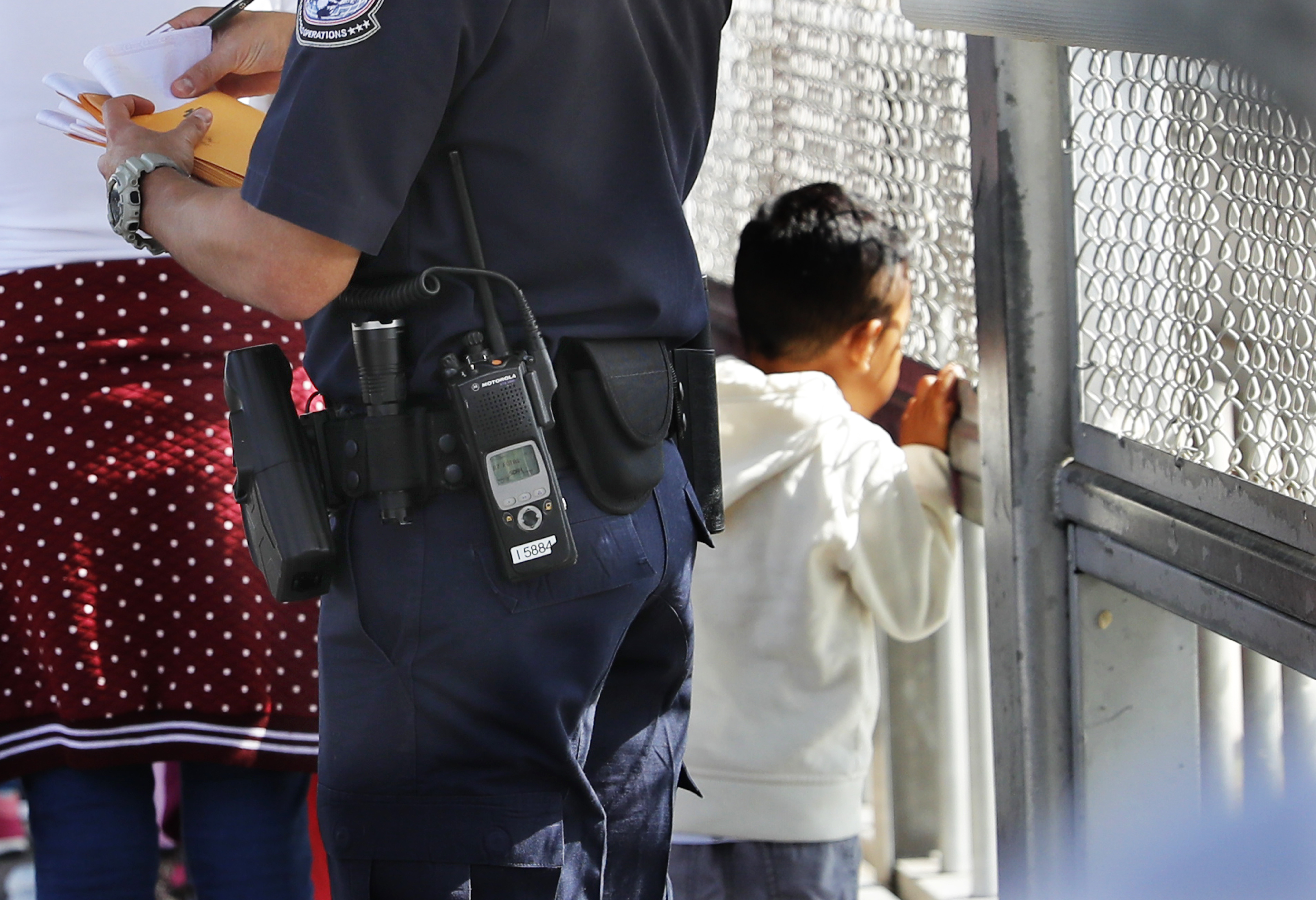 A United States Customs and Border Protection Officer checks the documents of migrants, before being taken to apply for asylum in the United States, on the International Bridge 1 in Nuevo Laredo, Mexico, Wednesday, July 17, 2019. Asylum-seekers grappled to understand what a new U.S. policy that all but eliminates refugee claims by Central Americans and many others meant for their bids to find a better life in America amid a chaos of rumors, confusion and fear. (AP Photo/Marco Ugarte)i