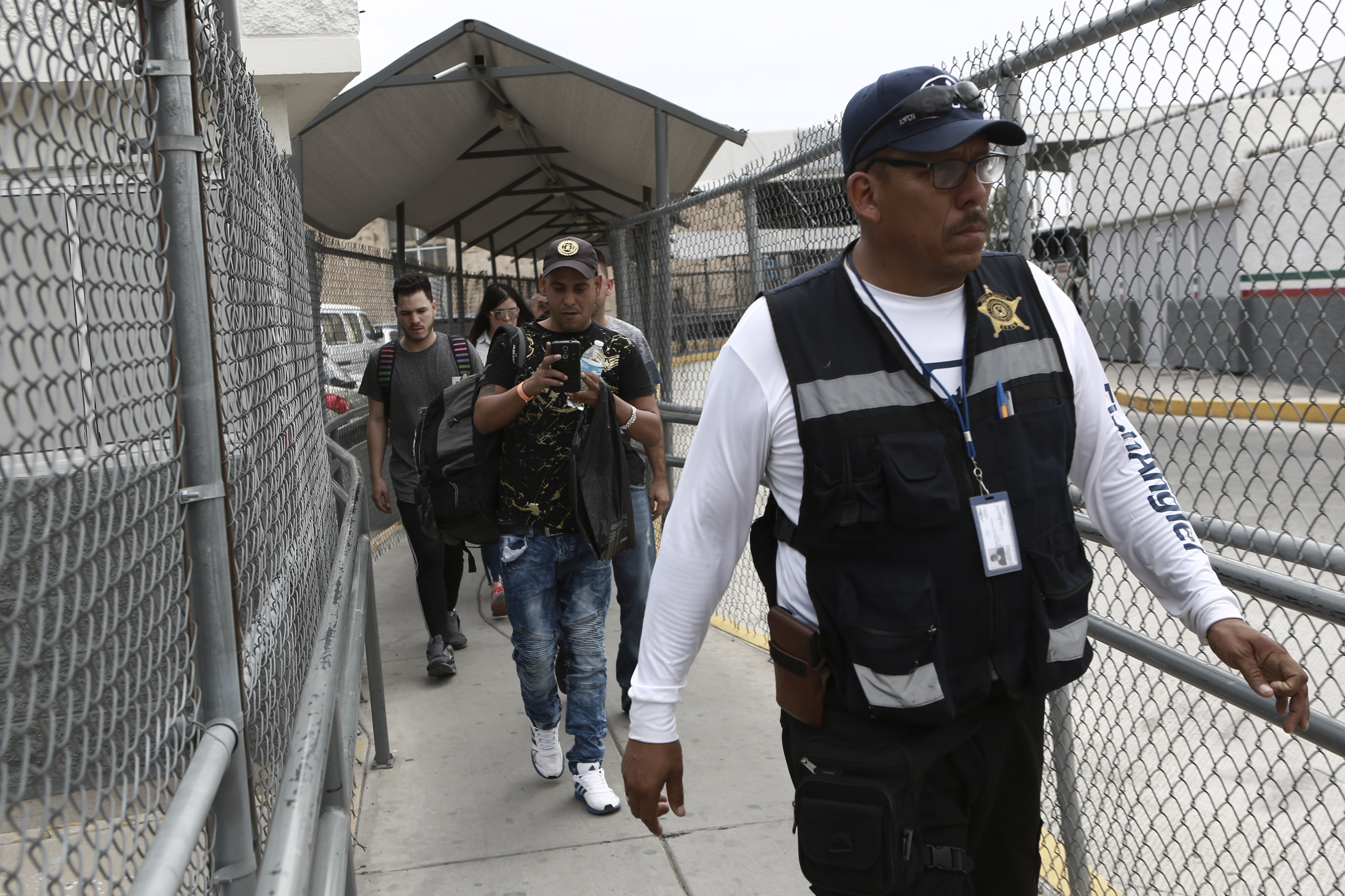 A security guard leads a group of U.S. asylum-seekers out of Mexican immigration offices after they were returned by U.S. authorities to wait in Mexico under the so-called Remain in Mexico program, in Ciudad Juarez, Mexico, Wednesday, July 17, 2019. Asylum-seekers still waiting to begin the process grappled to understand what a new U.S. policy that all but eliminates refugee claims by Central Americans and many others meant for their bids to find a better life in America. (AP Photo/Christian Chavez)