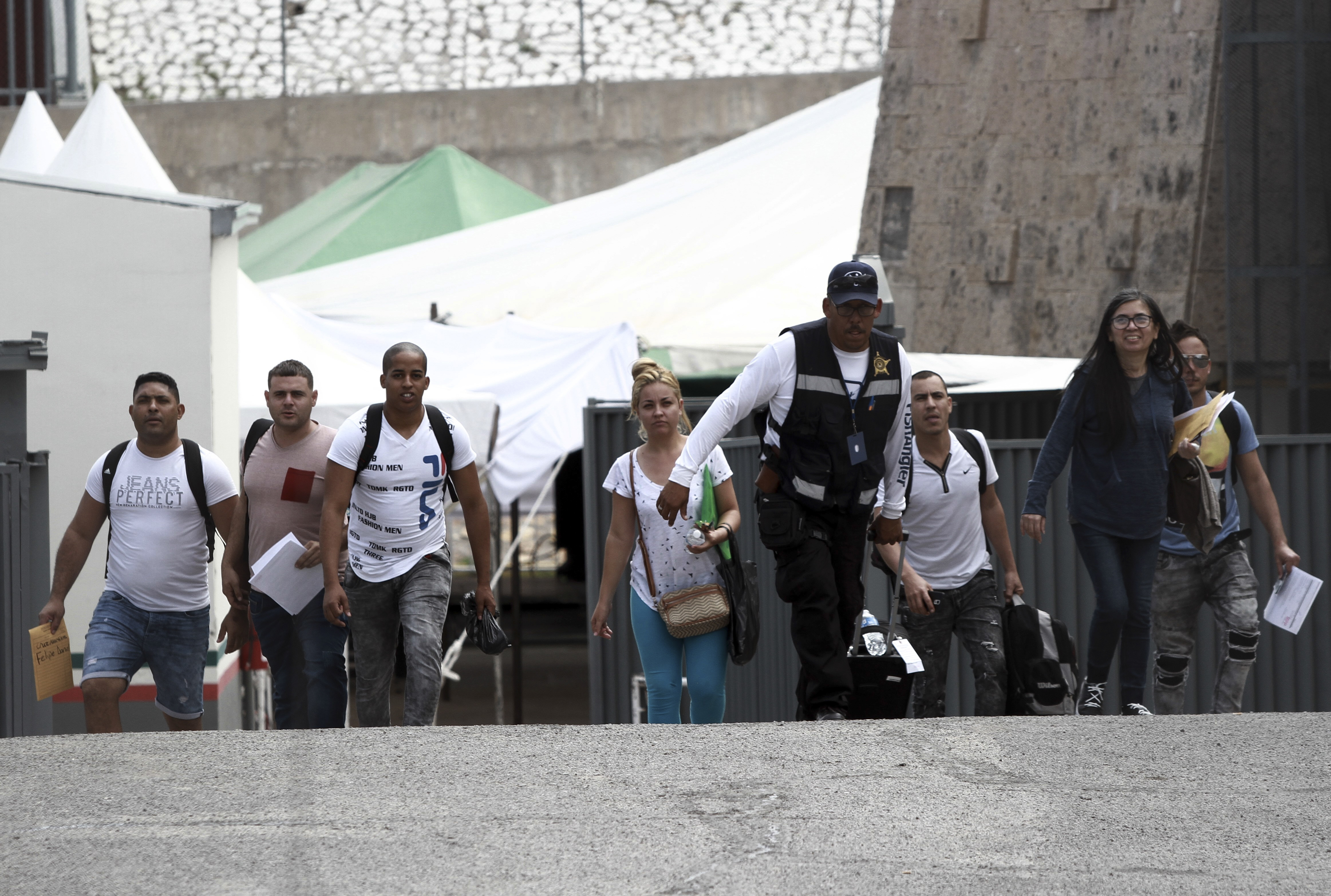 A security guard leads a group of U.S. asylum-seekers out of Mexican immigration offices after they were returned by U.S. authorities to wait in Mexico under the so-called Remain in Mexico program, in Ciudad Juarez, Mexico, Wednesday, July 17, 2019. Asylum-seekers still waiting to begin the process grappled to understand what a new U.S. policy that all but eliminates refugee claims by Central Americans and many others meant for their bids to find a better life in America.(AP Photo/Christian Chavez)