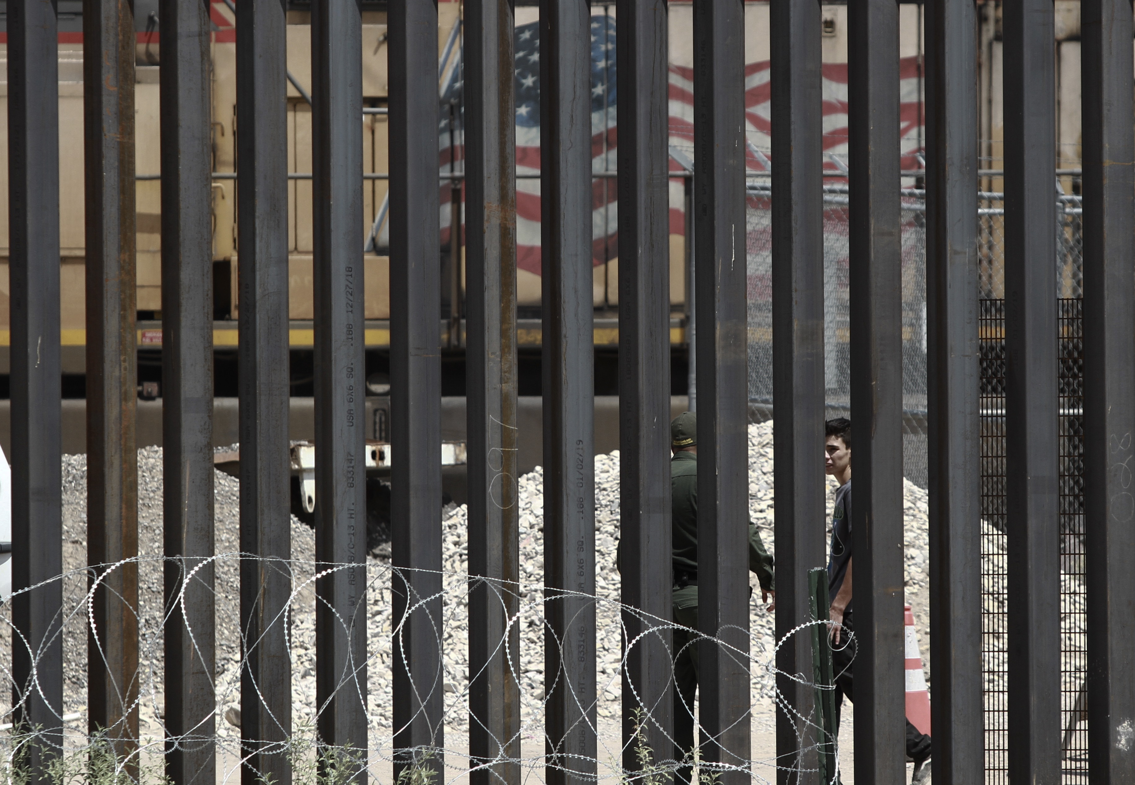 A Border Patrol agent escorts one of three migrants who had managed to evade Mexican National Guard and cross the Rio Grande onto U.S. territory toward a waiting patrol car, in El Paso, Texas, as seen from Ciudad Juarez, Mexico, Wednesday, July 17, 2019. Under a new U.S. policy that went into effect Tuesday, it was not clear whether the migrants would still be able to submit a claim for asylum after reaching U.S. soil and surrendering to Border Patrol. (AP Photo/Christian Chavez)