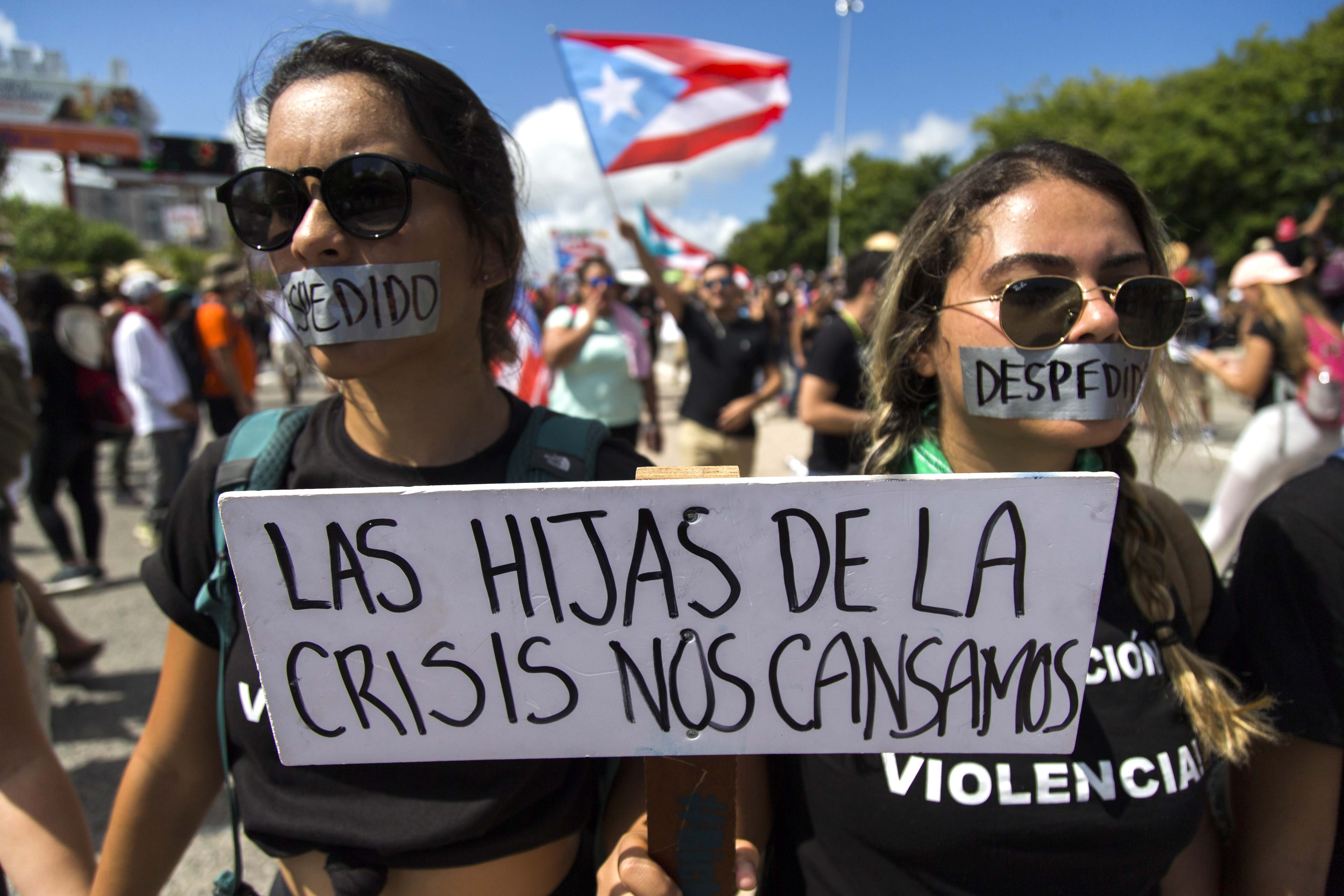 Demonstrators with their mouths covered with a tape and a sign that reads in Spanish 