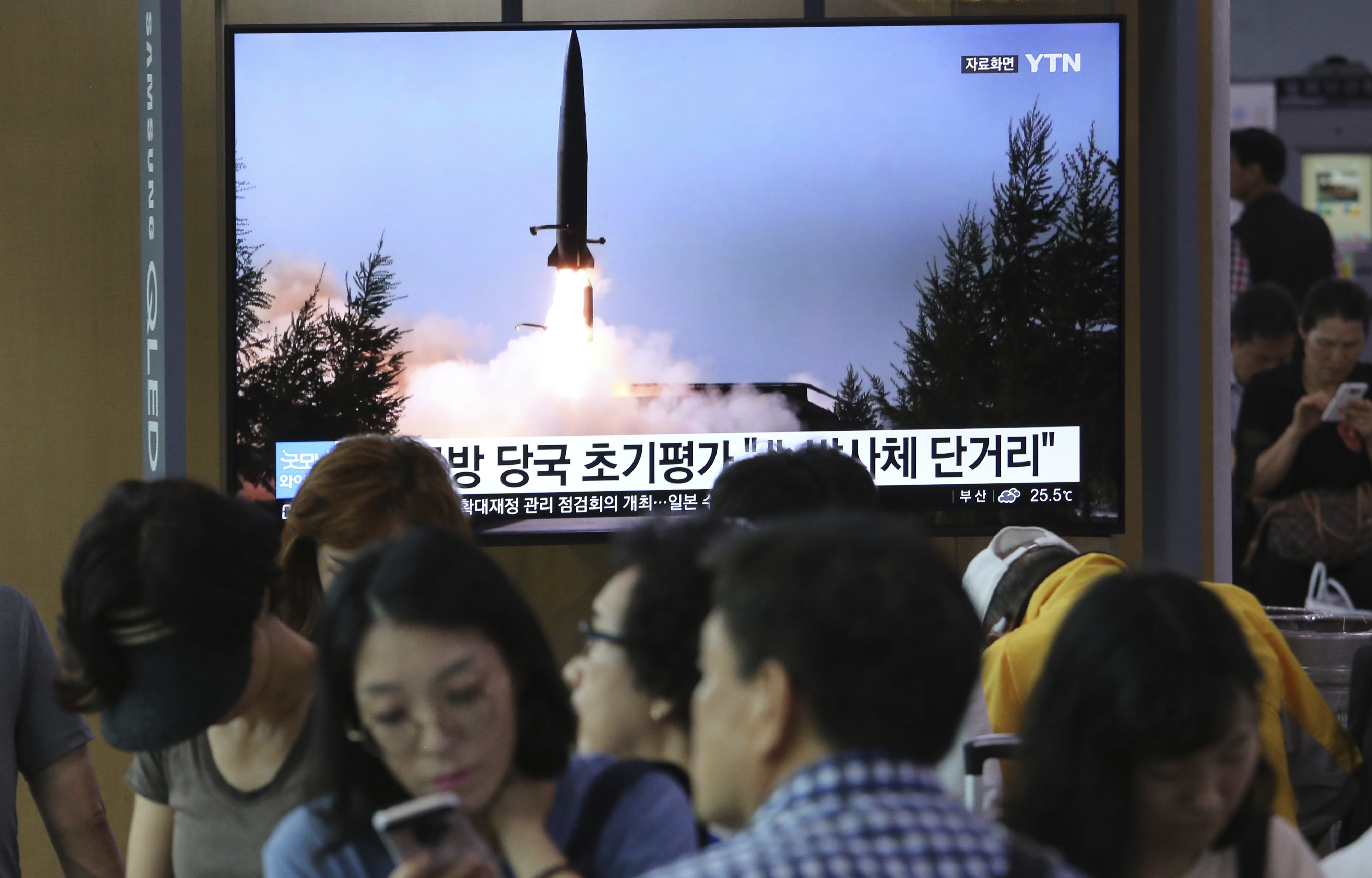 People watch a TV showing a file image of North Korea's missile launch during a news program at the Seoul Railway Station in Seoul, South Korea, Thursday, July 25, 2019. North Korea fired two unidentified projectiles into the sea on Thursday, South Korea's military said, the first launches in more than two months as North Korean and U.S. officials work to restart nuclear diplomacy. The signs read: 
