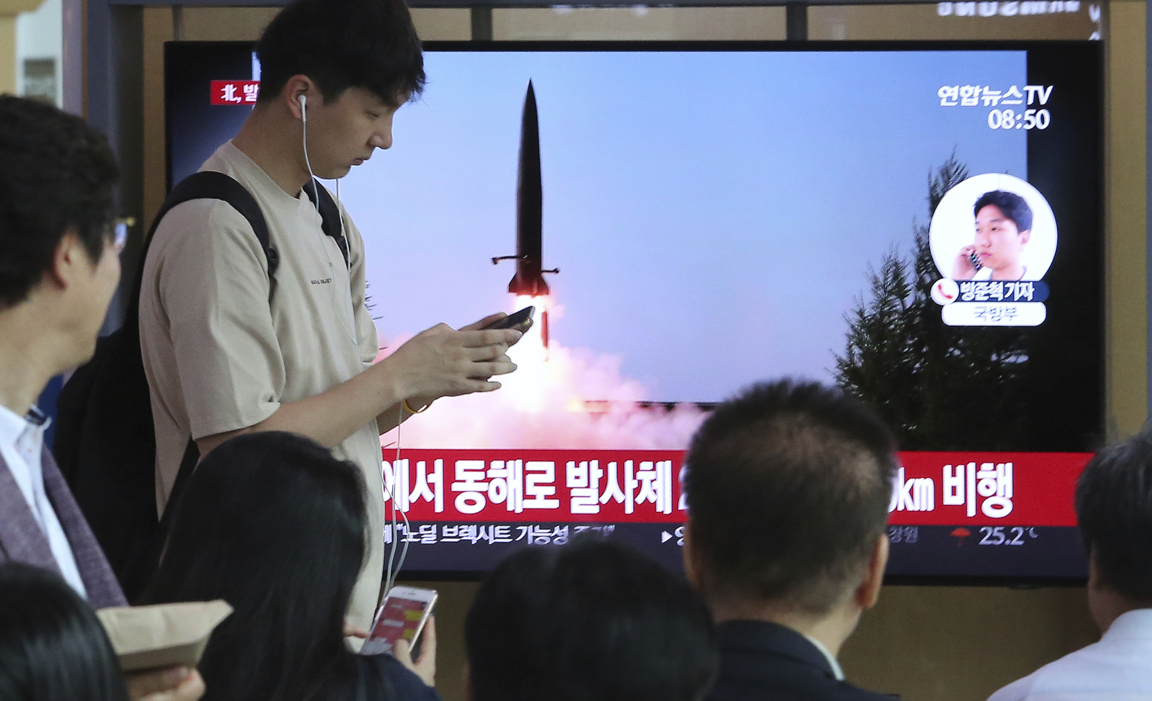 People watch a TV showing a file image of North Korea's missile launch during a news program at the Seoul Railway Station in Seoul, South Korea, Thursday, July 25, 2019. North Korea fired two unidentified projectiles into the sea on Thursday, South Korea's military said, the first launches in more than two months as North Korean and U.S. officials work to restart nuclear diplomacy. The signs read: 