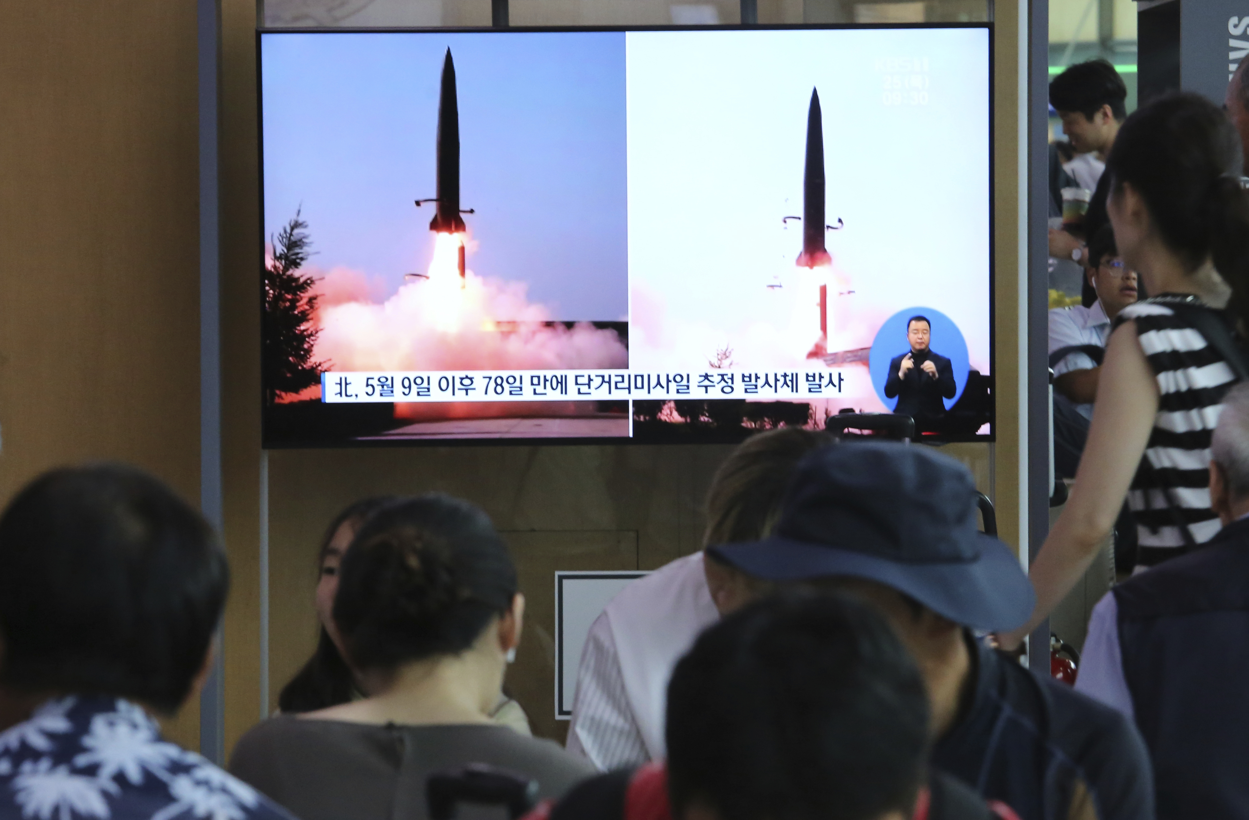 People watch a TV showing file images of North Korea's missile launch during a news program at the Seoul Railway Station in Seoul, South Korea, Thursday, July 25, 2019. North Korea fired two unidentified projectiles into the sea on Thursday, South Korea's military said, the first launches in more than two months as North Korean and U.S. officials struggle to restart nuclear diplomacy. The signs read: 