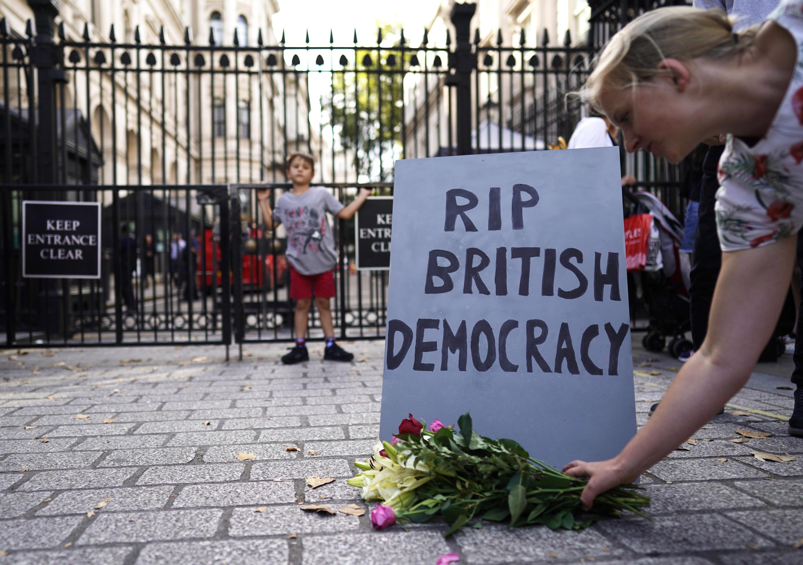 epa07799380 A protester lays flowers in front of a mock tombstone, during a protest outside the gates of Number 10 Downing Street in Westminster, London, Britain, 28 August 2019. The UK government is to suspend Parliament after the summer break, a move that might block MPs from voting against a possible no-deal Brexit. In a letter to legislators, British PM Boris Johnson said he had asked Queen Elizabeth II to suspend the current parliamentary session in the second week of September until 14 October.  EPA/WILL OLIVER