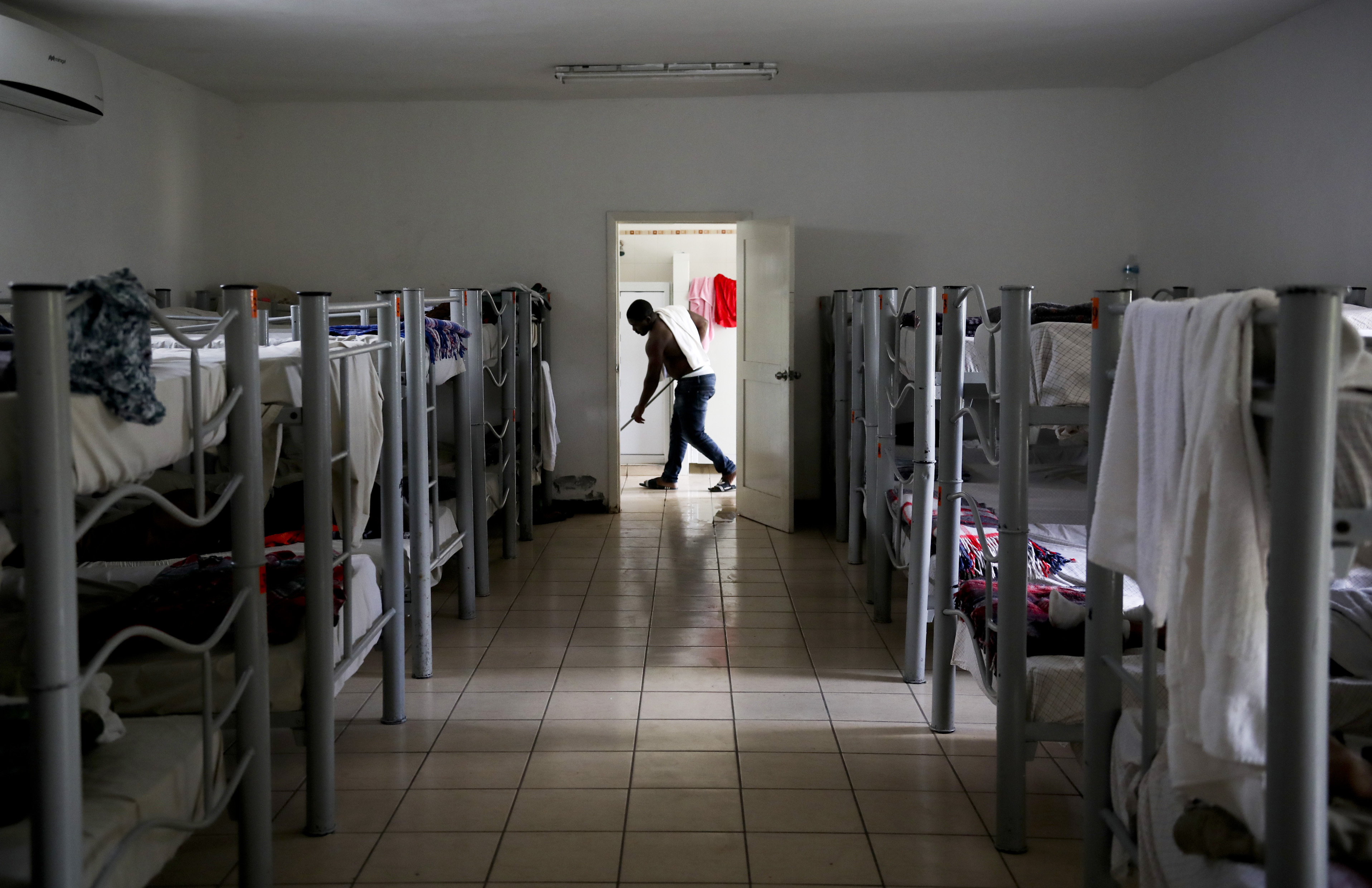 A migrant from Cameroon cleans the floor of 