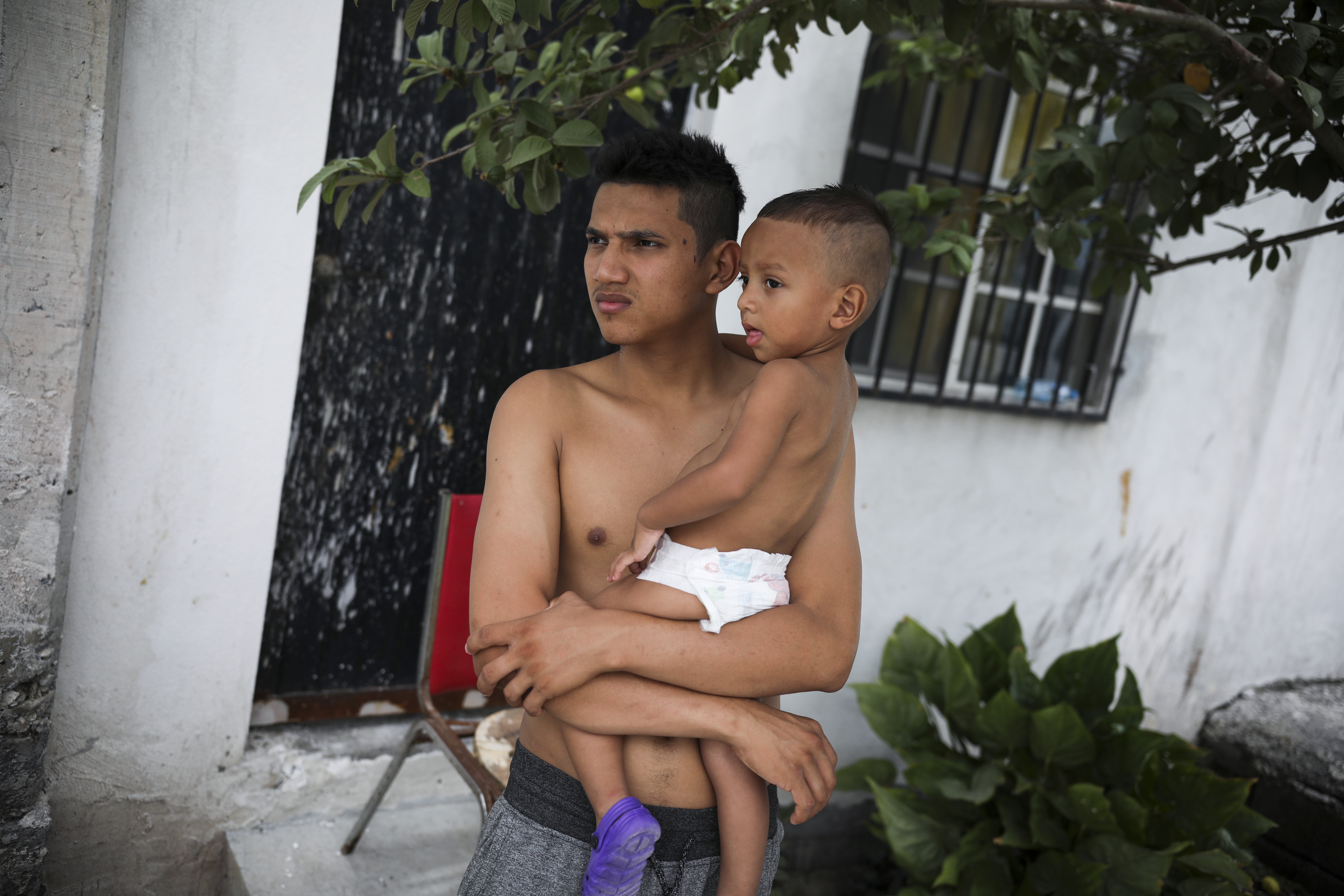 Gerardo, a 23-year-old migrant from Honduras who did not want to give his last name, holds his son Orlando outside the Viento Recio church, which is serving as a migrant shelter, in Matamoros, Mexico, Thursday, Aug. 1, 2019, on the border with Brownsville, Texas. Some migrants are waiting for their names to be called from a list more than 1,000 names long to apply for asylum in the U.S. while others have recently been returned and are awaiting court dates. (AP Photo/Emilio Espejel)