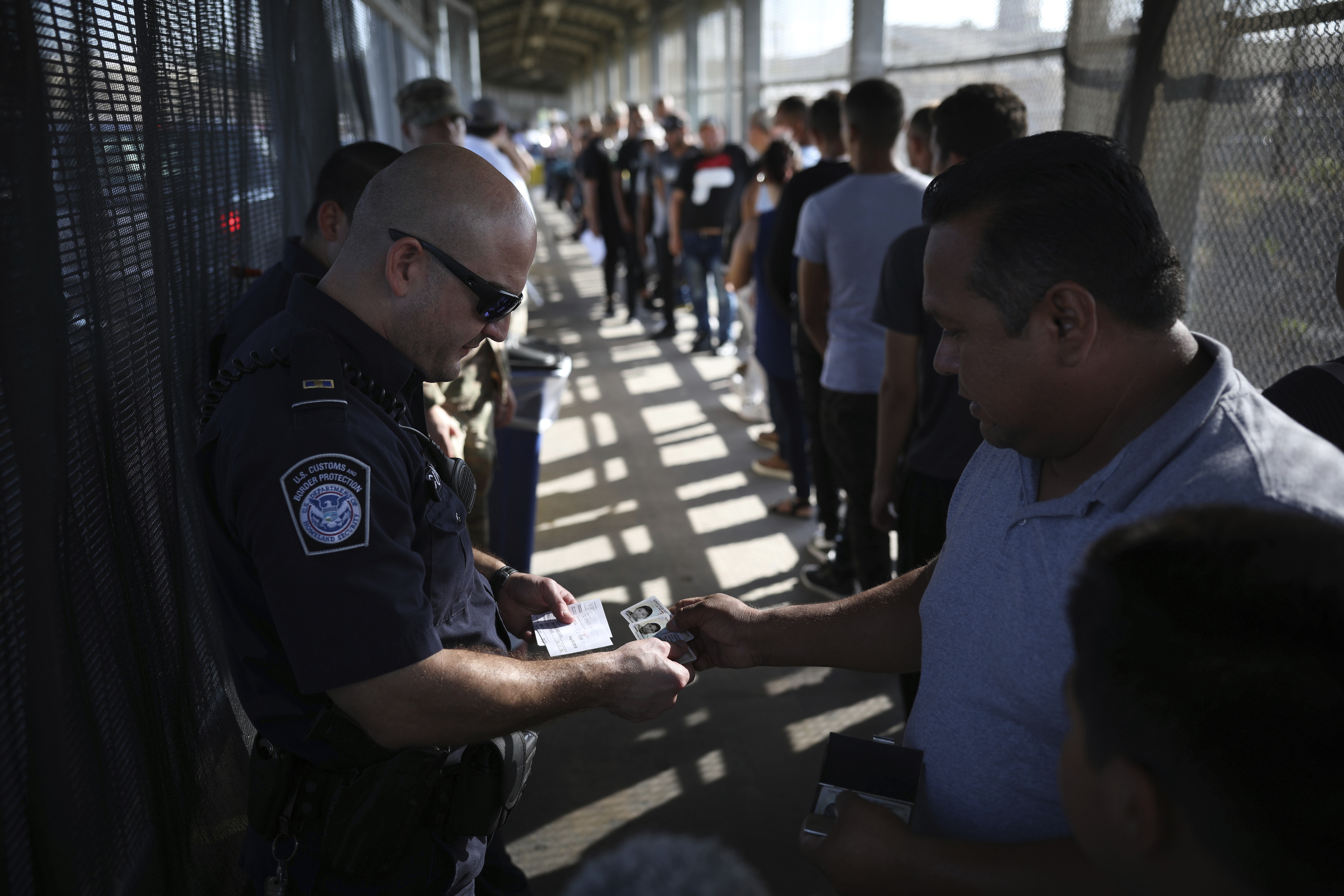 CORRECTS DATE - U.S Customs officer verifies the Visas of a man and his family at the foot of the Puerta Mexico bridge that crosses into Brownsville, Texas, in Matamoros, Mexico, Friday, Aug. 2, 2019. (AP Photo/Emilio Espejel)