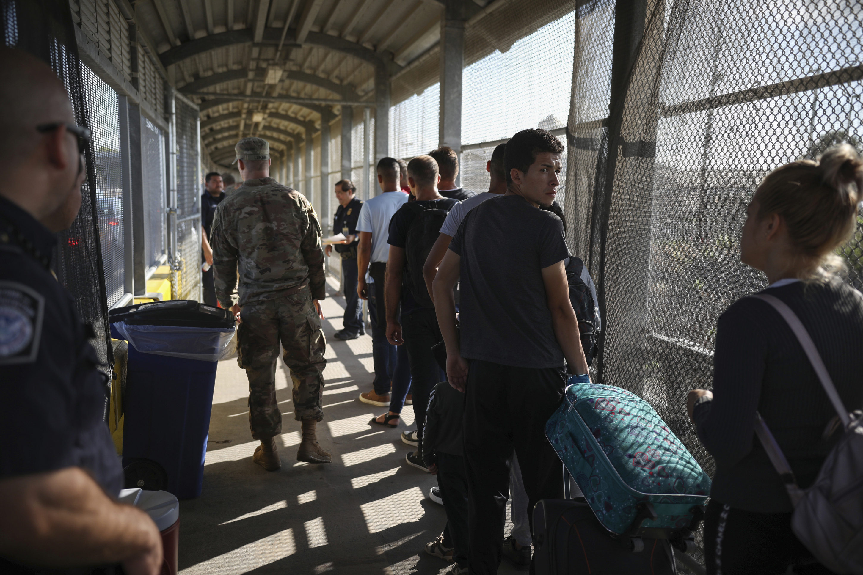 CORRECTS DATE - Migrants line up on their way to request asylum in the U.S., at the foot of the Puerta Mexico bridge that crosses to Brownsville, Texas, into Matamoros, Mexico, Friday, Aug. 2, 2019. (AP Photo/Emilio Espejel)