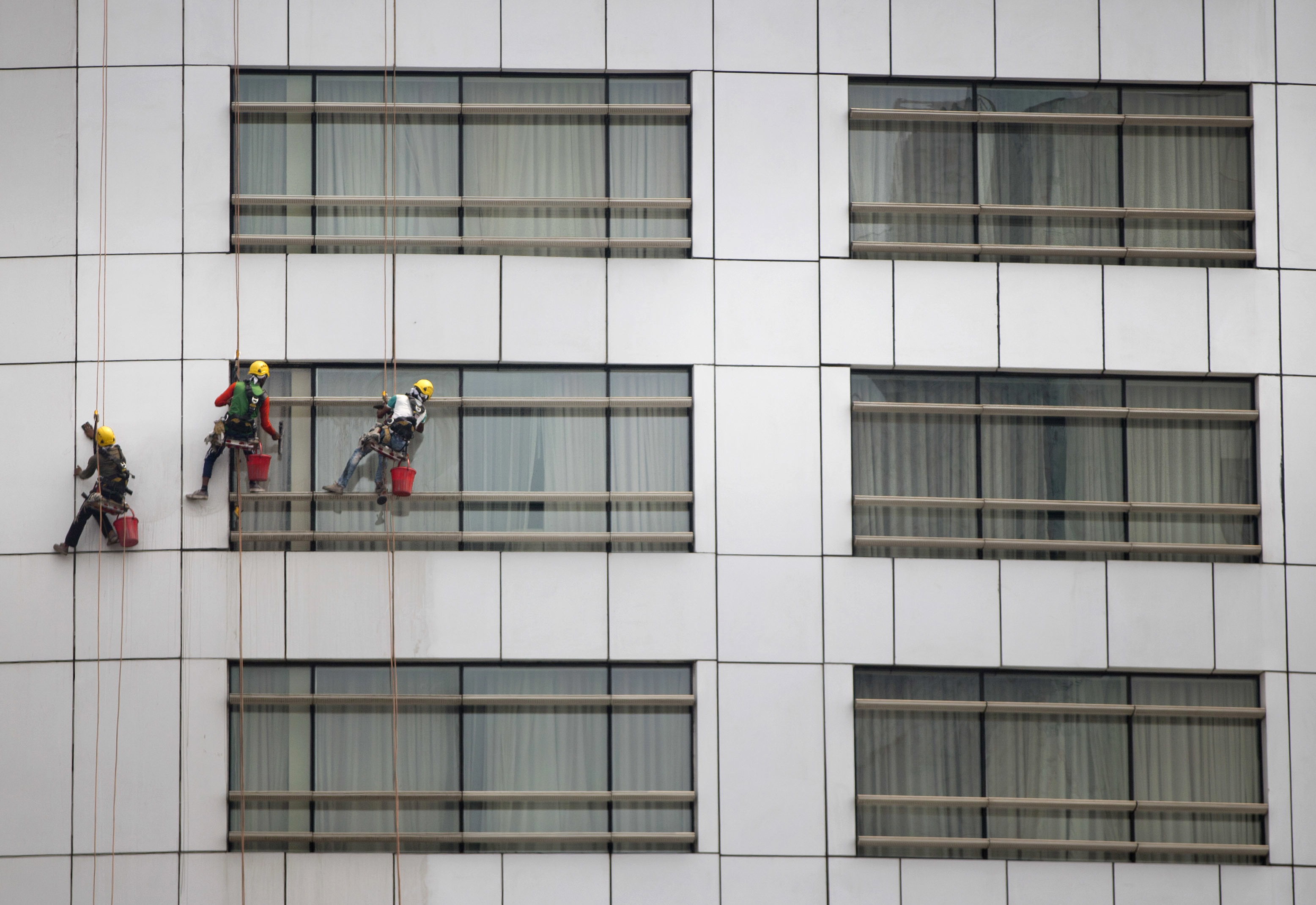 Window cleaners work on glass panes of an office building in Dhaka, Bangladesh, Saturday, March 24, 2018. On an average, each worker earns less than US$5 a day. (AP Photo/A.M. Ahad)