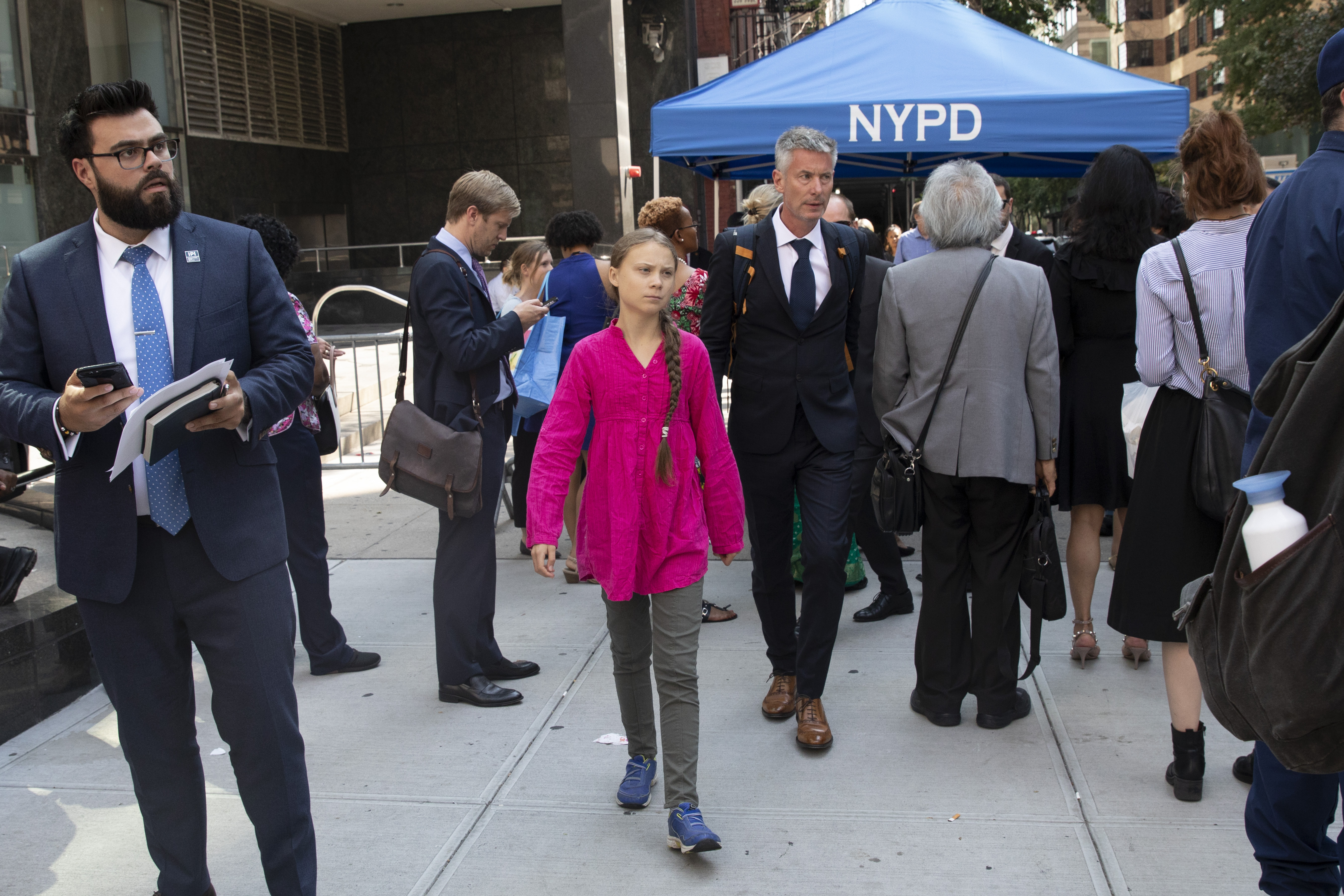 Environmental activist Greta Thunberg, center, of Sweden, walks with an entourage after passing a security checkpoint while appearing at the United Nations, Monday, Sept. 23, 2019 in New York. (AP Photo/Mark Lennihan)