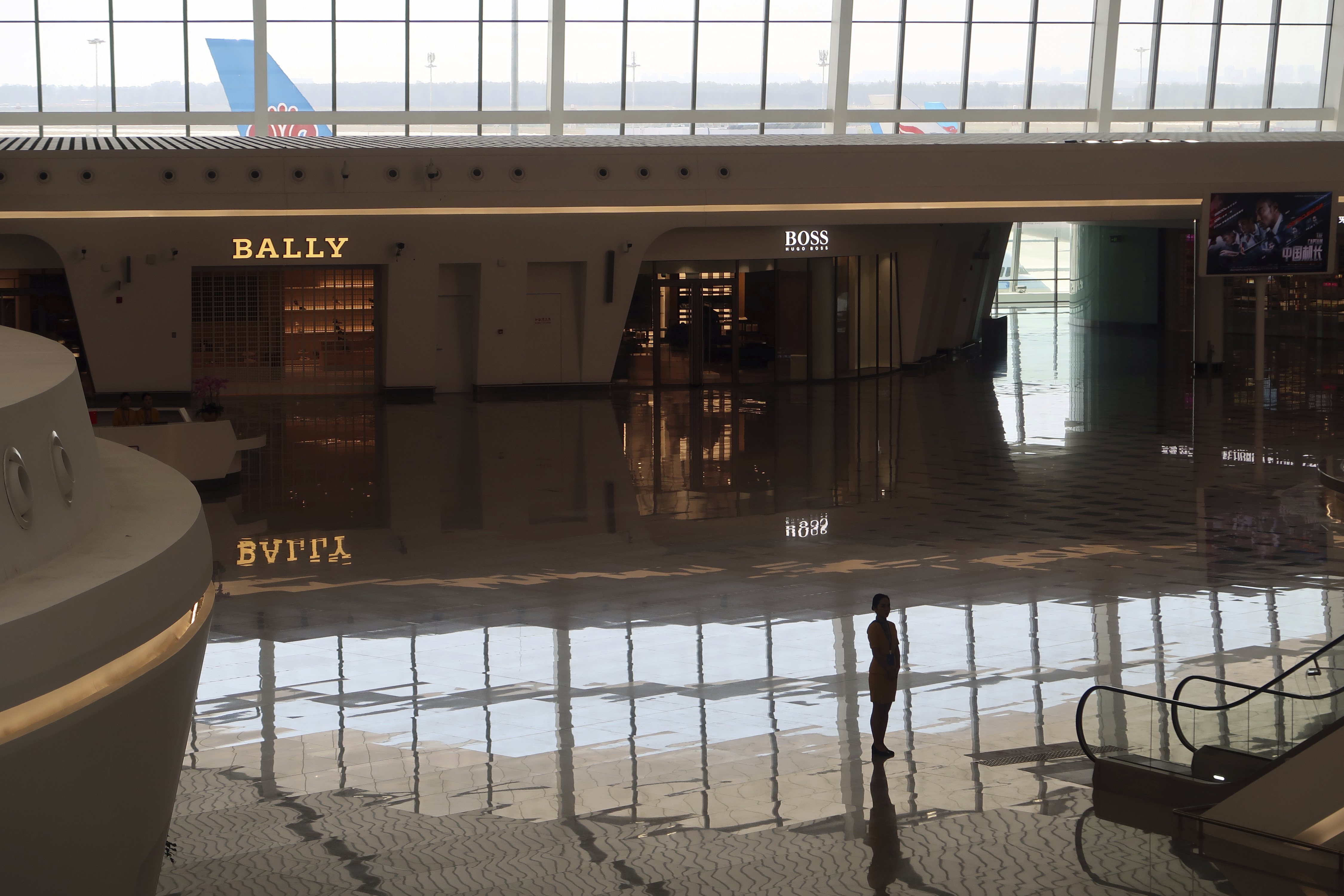 A staff member stands near shops at the terminal hall of the new Daxing International Airport following its launching ceremony ahead of the 70th founding anniversary of the People's Republic of China in Beijing, China Wednesday, Sept. 25, 2019. (Thomas Suen/Pool Photo via AP)