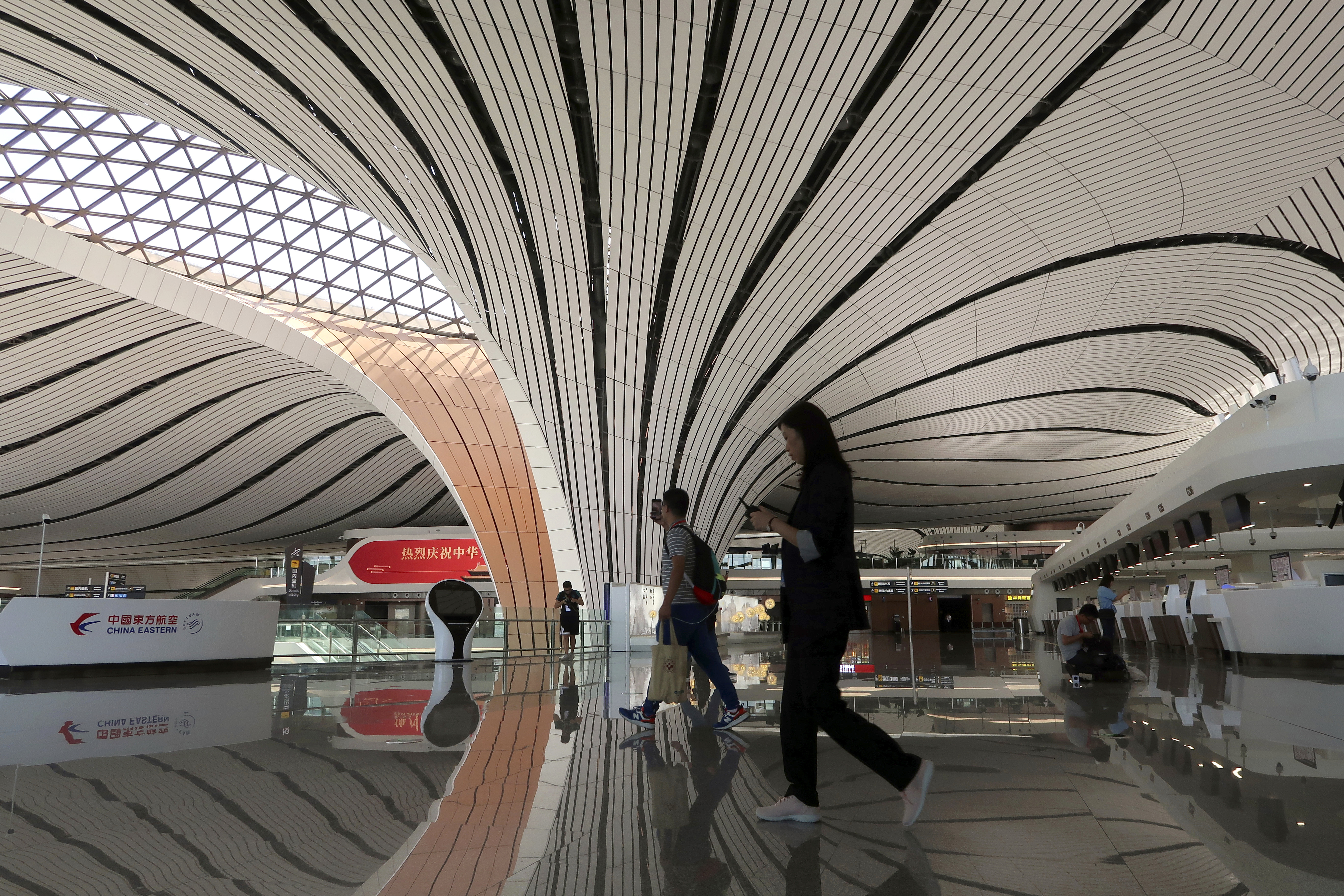 Journalists walk at the terminal hall after the launching ceremony for the new Daxing International Airport ahead of the 70th founding anniversary of the People's Republic of China in Beijing, China  Wednesday, Sept. 25, 2019. (Thomas Suen/Pool Photo via AP)