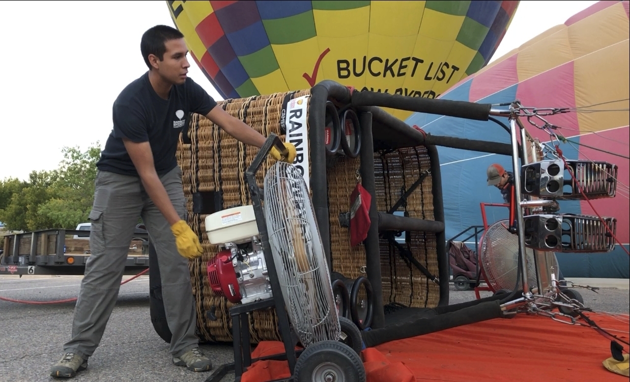 Elijah Sanchez starts a fan to inflating a hot air balloon in Albuquerque, N.M., on Tuesday, Oct. 1, 2019. Sanchez, 20, will be among the youngest pilots to launch as part of this year's Albuquerque International Balloon Fiesta. The nine-day event is expected to draw several hundred thousand spectators and hundreds of balloonists from around the world. It will kick off Oct. 5 with a mass ascension. (AP Photo/Susan Montoya Bryan)