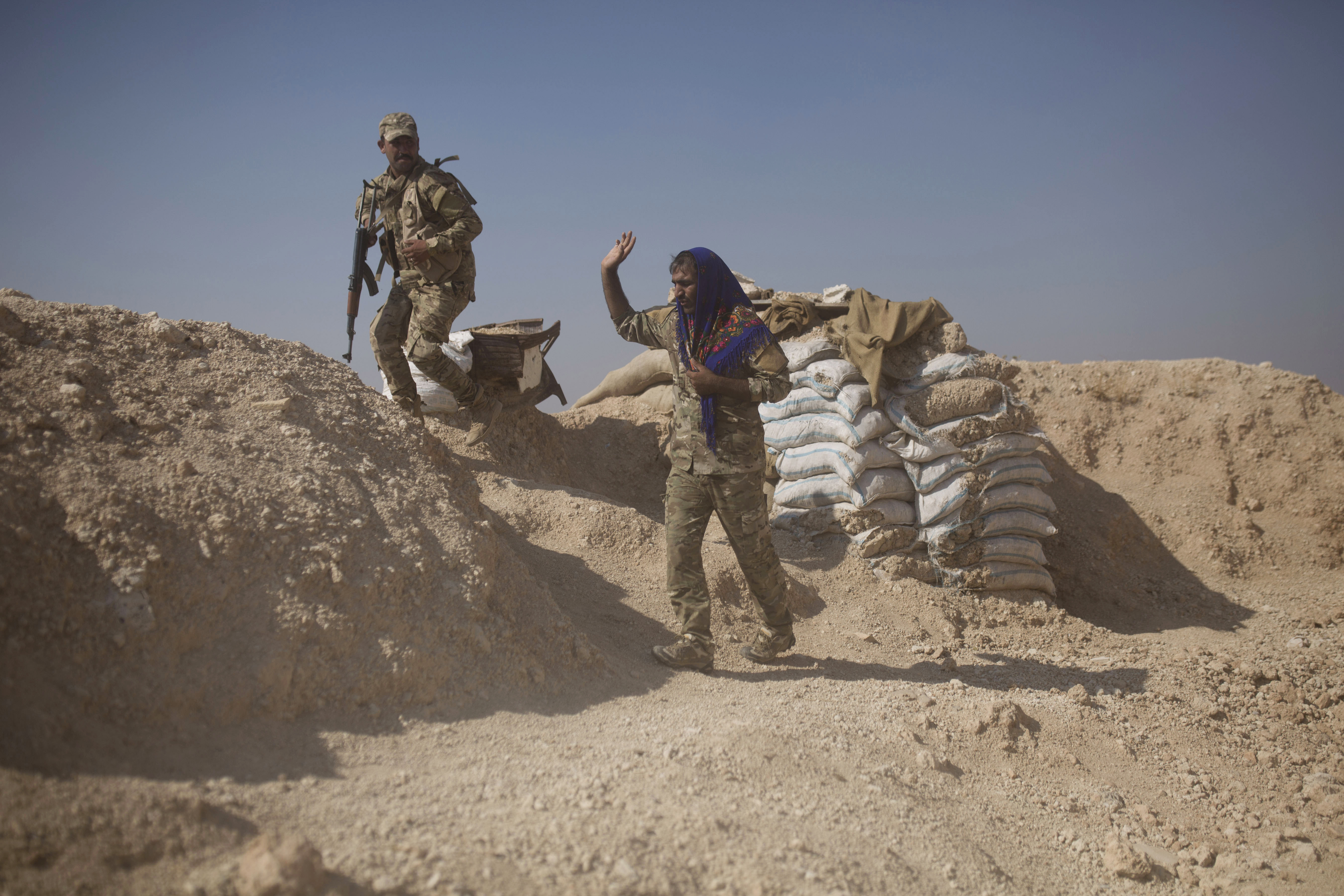 A member of the Tal Abyad Military Council, an affiliate of the U.S.-backed Syrian Democratic Forces, waves a comrade away from his post before collapsing the site in the safe zone between Syria and the Turkish border near Tal Abyad, Syria, Friday, Sept. 6, 2019. Once part of the sprawling territories controlled by the Islamic State group, the villages are under threat of an attack from Turkey which considers their liberators, the U.S-backed Syrian Kurdish-led forces, terrorists.T o forestall violence between its two allies along the border it has helped clear of IS militants, Washington has upped its involvement in this part of Syria.. (AP Photo/Maya Alleruzzo)