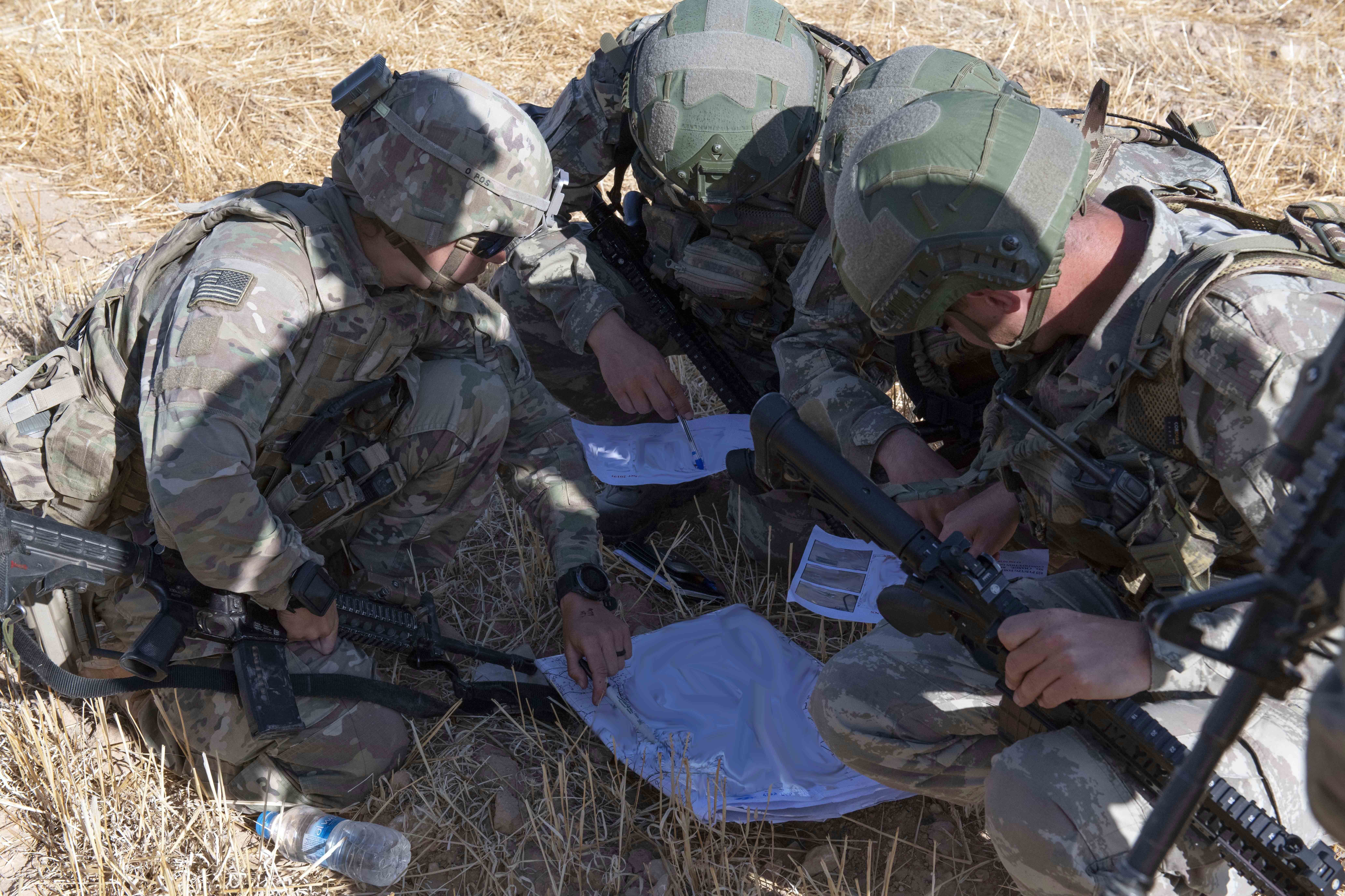 In this In this Sept. 24, 2019, photo, released by the U.S. Army, U.S. and Turkish military forces go over a map in preparation of their second joint ground patrol inside the so-called 