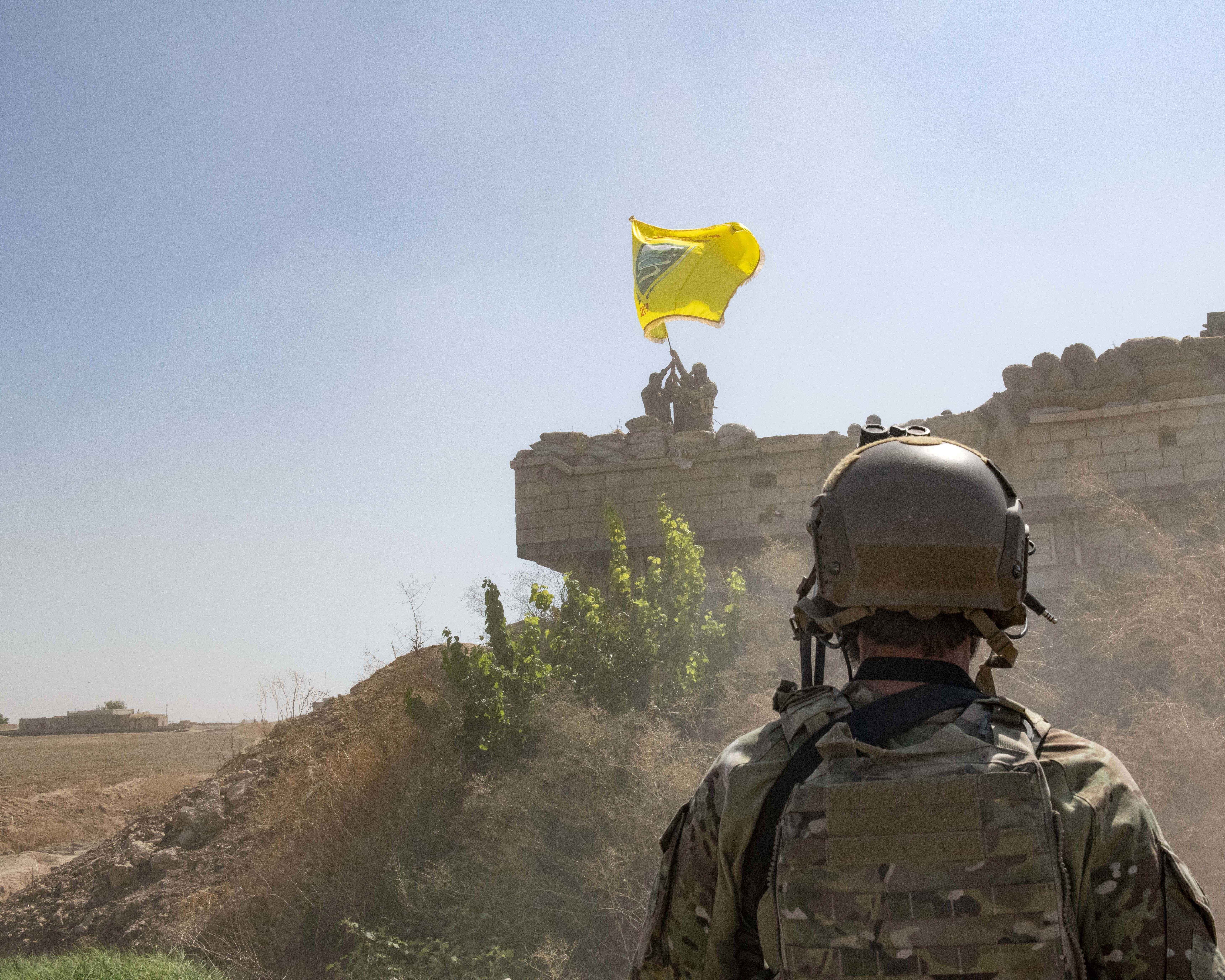 In this Sept. 21, 2019, photo, released by the U.S. Army, a U.S. soldier oversees members of the Syrian Democratic Forces as they demolish a Kurdish fighters' fortification and raise a Tal Abyad Military Council flag over the outpost as part of the so-called 