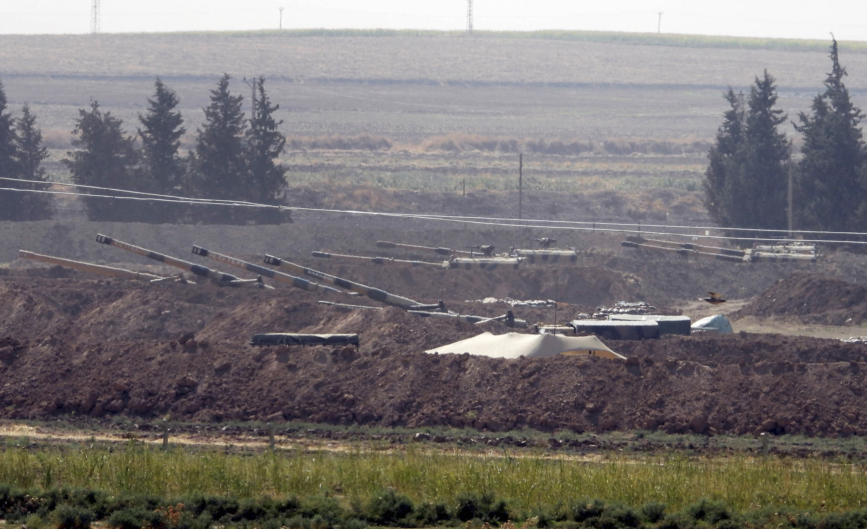 In this Sunday, Oct. 6, 2019 photo, Turkish forces artillery pieces are seen on their new positions near the border with Syria in Sanliurfa province, Turkey. U.S.-backed Kurdish-led forces in Syria said American troops began withdrawing Monday from their positions along Turkey's border in northeastern Syria, ahead of an anticipated Turkish invasion that the Kurds say will overturn five years of achievements in the battle against the Islamic State group. (DHA via AP)