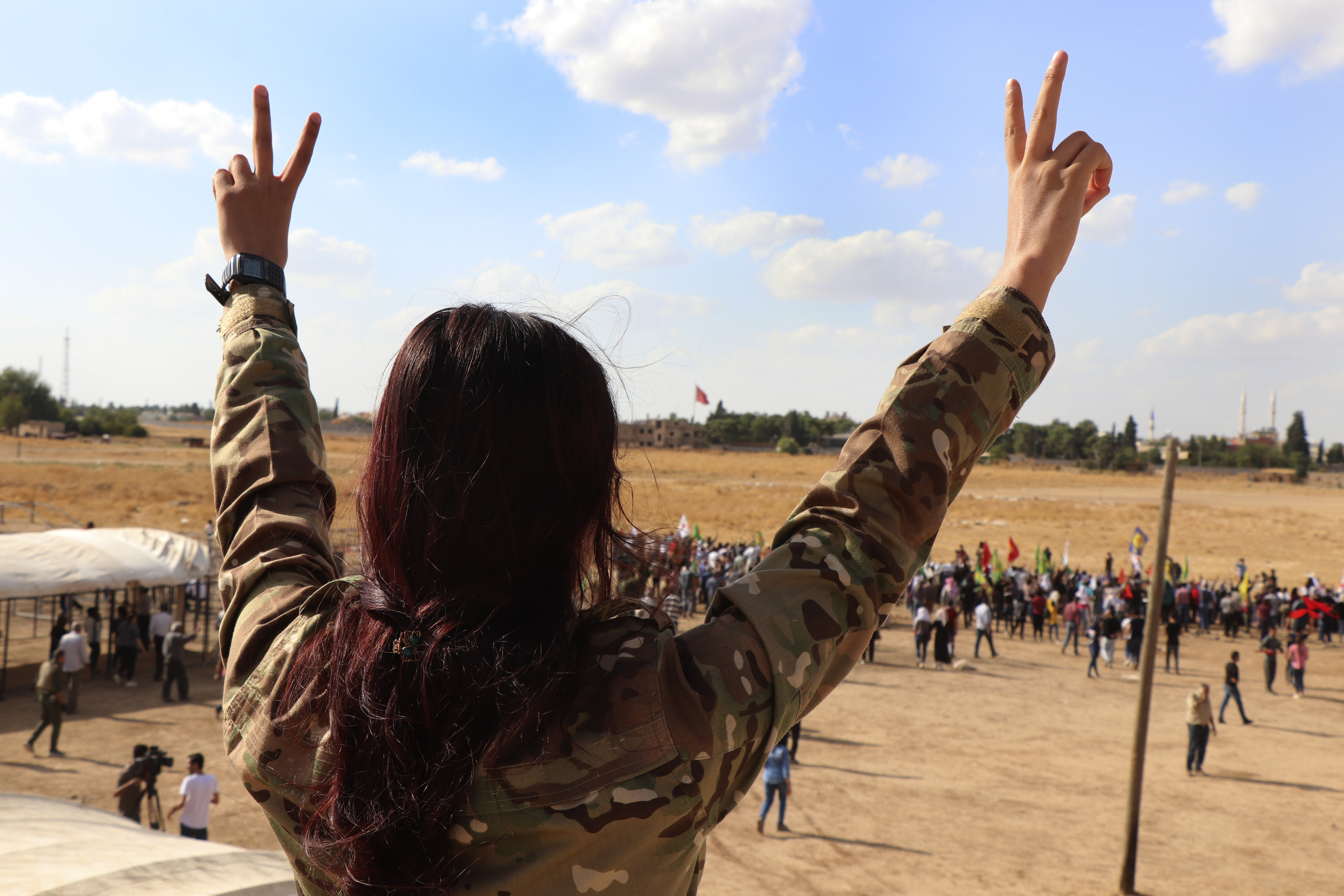 A fighter from the Syrian Democratic Forces, SDF, flashes the victory sign during a demonstration against possible Turkish military operation on their areas, at the Syrian-Turkish border, in Ras al-Ayn, Syria, Monday, Oct. 7, 2019. Syria's Kurds accused the U.S. of turning its back on its allies and risking gains made in the fight against the Islamic State group as American troops began pulling back on Monday from positions in northeastern Syria ahead of an expected Turkish assault. (AP Photo)