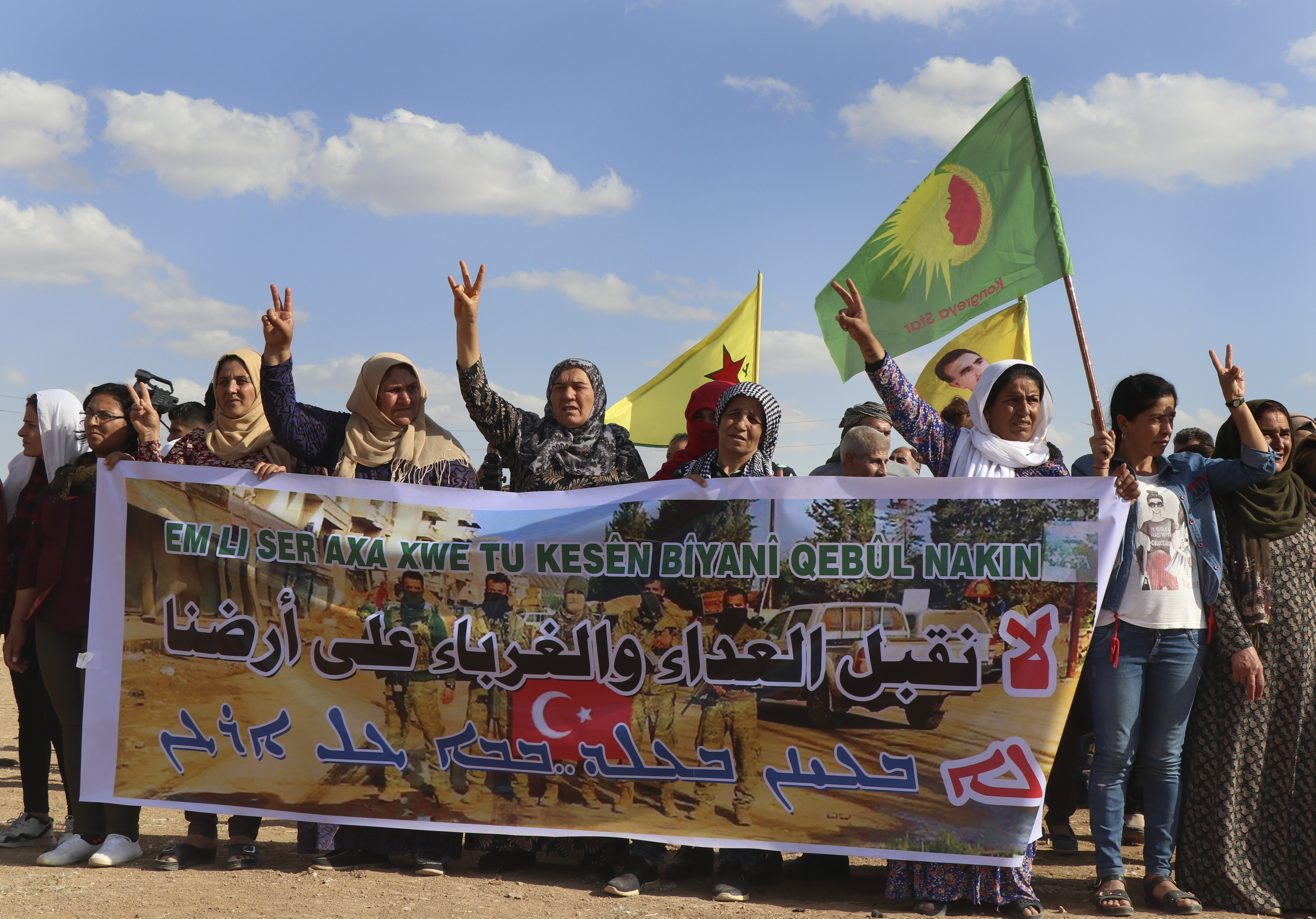 Kurdish women hold a banner with Arabic that read, 