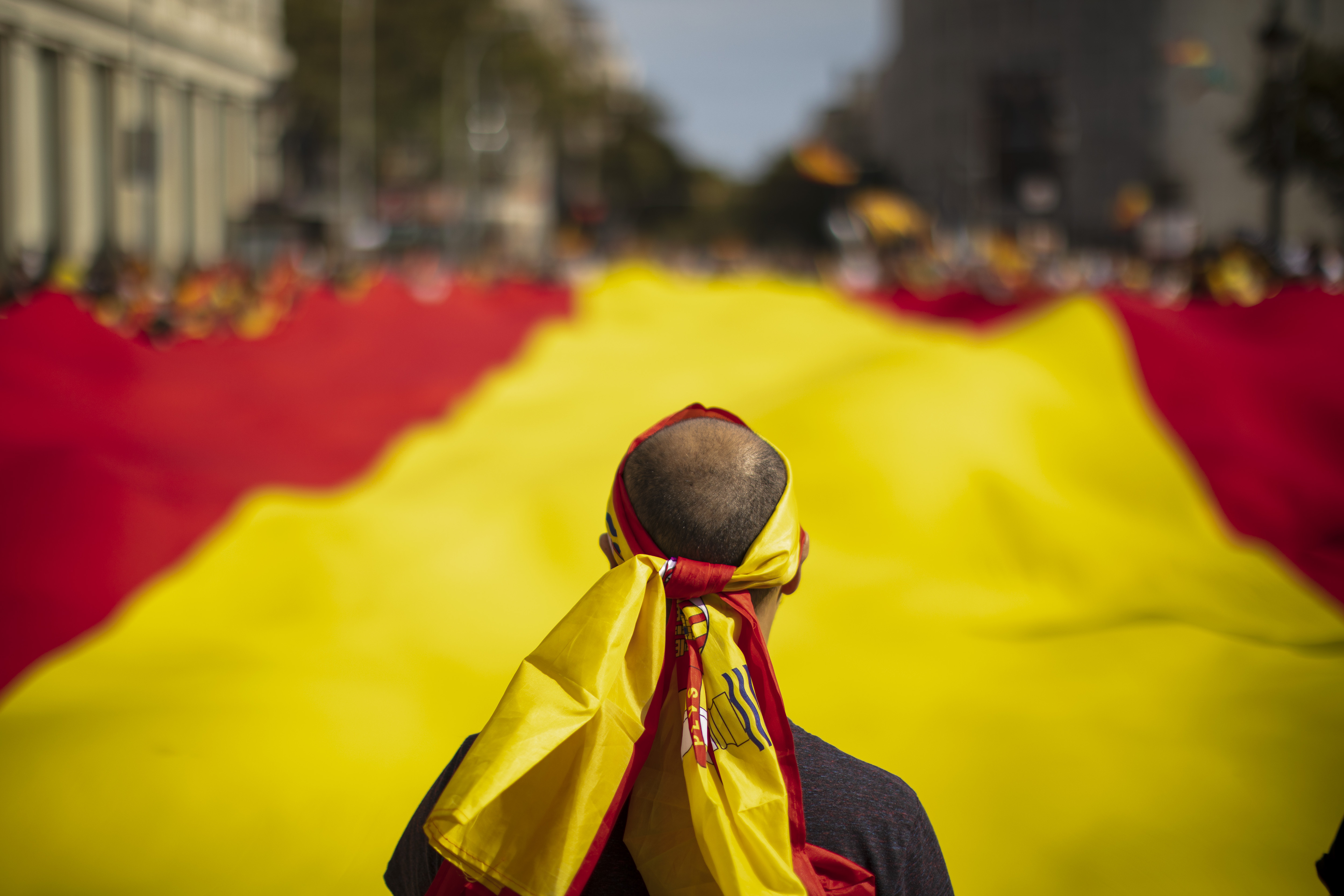 People hold a huge Spanish flag as they celebrate a holiday known as 