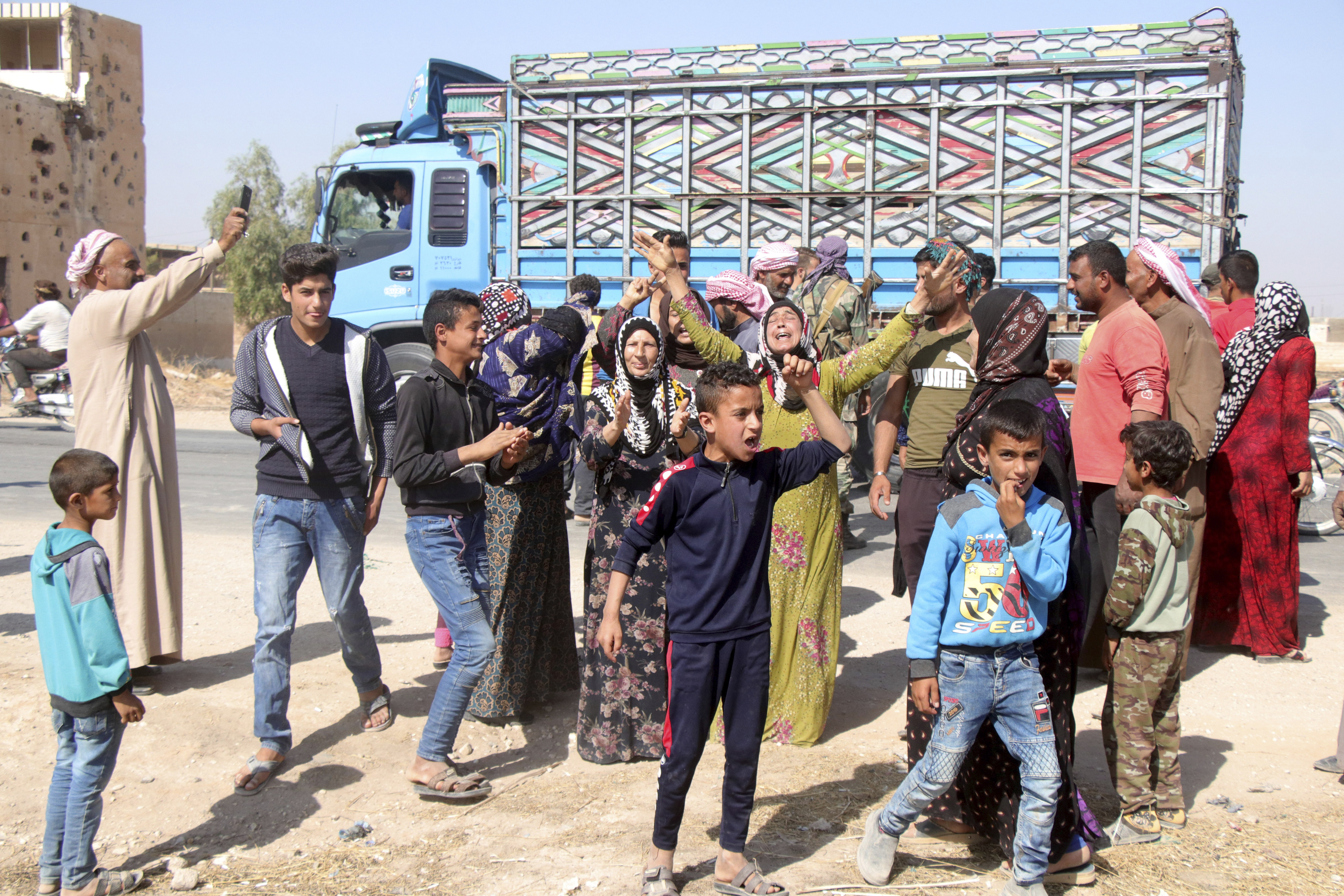 People welcome Syrian troops as they enter the village of Ghebesh, west of the town of Tal Tamr, in northern Syria, Monday, Oct 14, 2019. Syrian government troops moved into towns and villages in northern Syria on Monday, setting up a potential clash with Turkish-led forces advancing in the area as long-standing alliances in the region begin to crumble following the pullback of U.S. forces. (AP Photo)