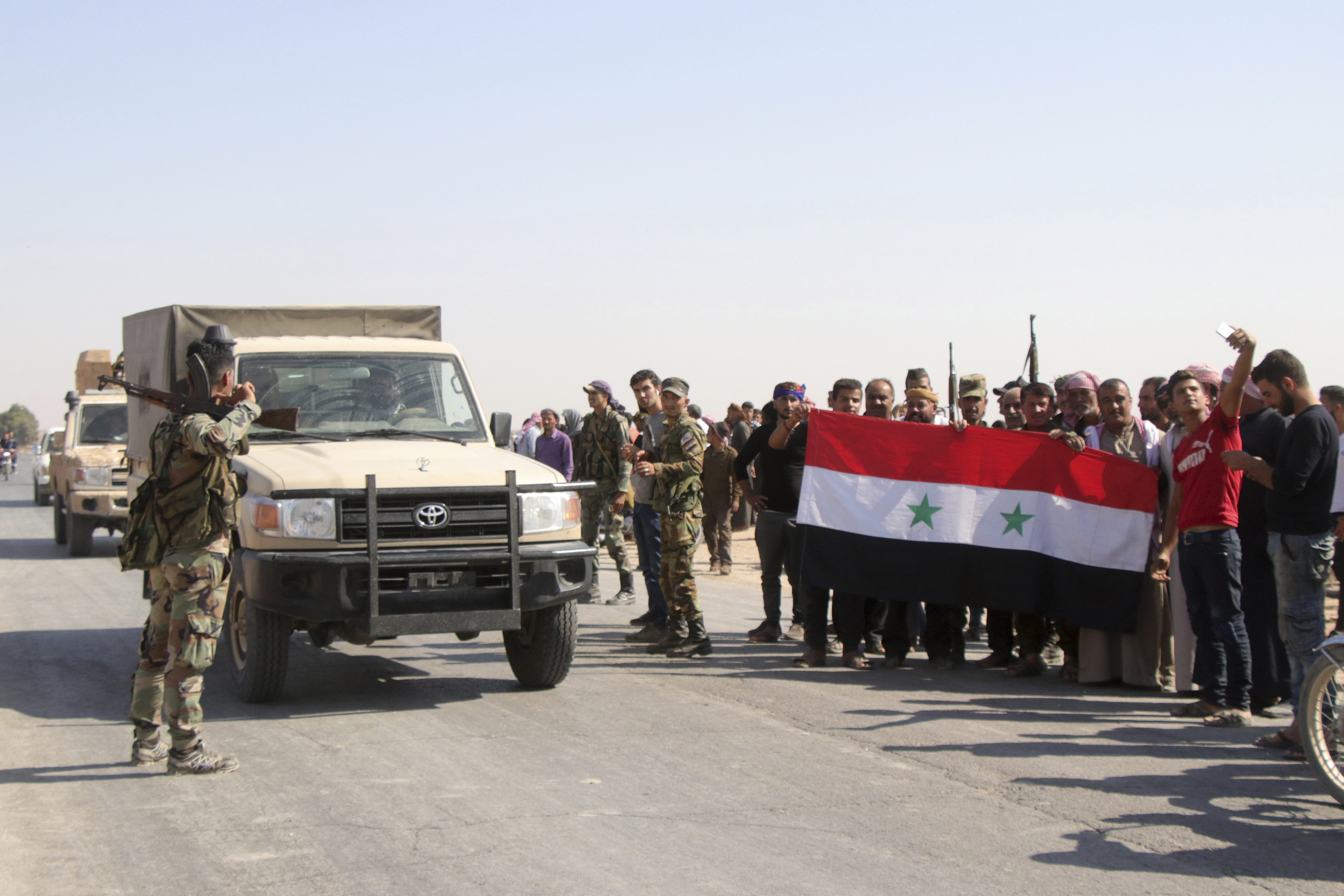 People welcome Syrian troops as they enter the village of Ghebesh, west of the town of Tal Tamr, in northern Syria, Monday, Oct 14, 2019. Syrian government troops moved into towns and villages in northern Syria on Monday, setting up a potential clash with Turkish-led forces advancing in the area as long-standing alliances in the region begin to crumble following the pullback of U.S. forces. (AP Photo)