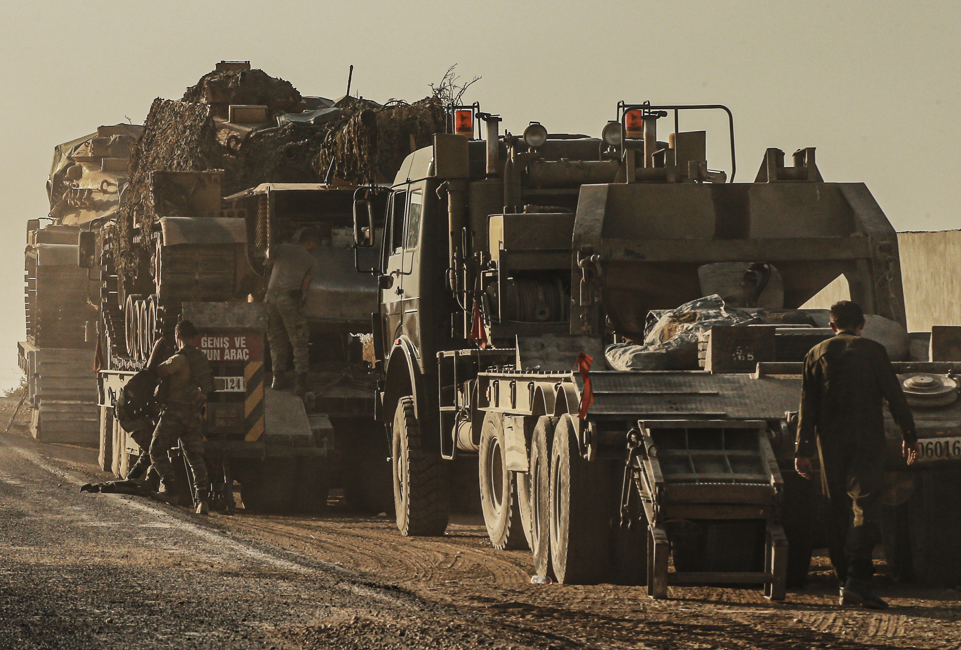 Turkish soldiers work on uploading tanks from trucks on a road towards the border of Syria in Sanliurfa province, Turkey, Monday, Oct. 14, 2019. Syrian troops entered several northern towns and villages Monday, getting close to the Turkish border as Turkey's army and opposition forces backed by Ankara marched south in the same direction, raising concerns of a clash between the two sides as Turkey's invasion of northern Syria entered its sixth day. (AP Photo/Emrah Gurel)