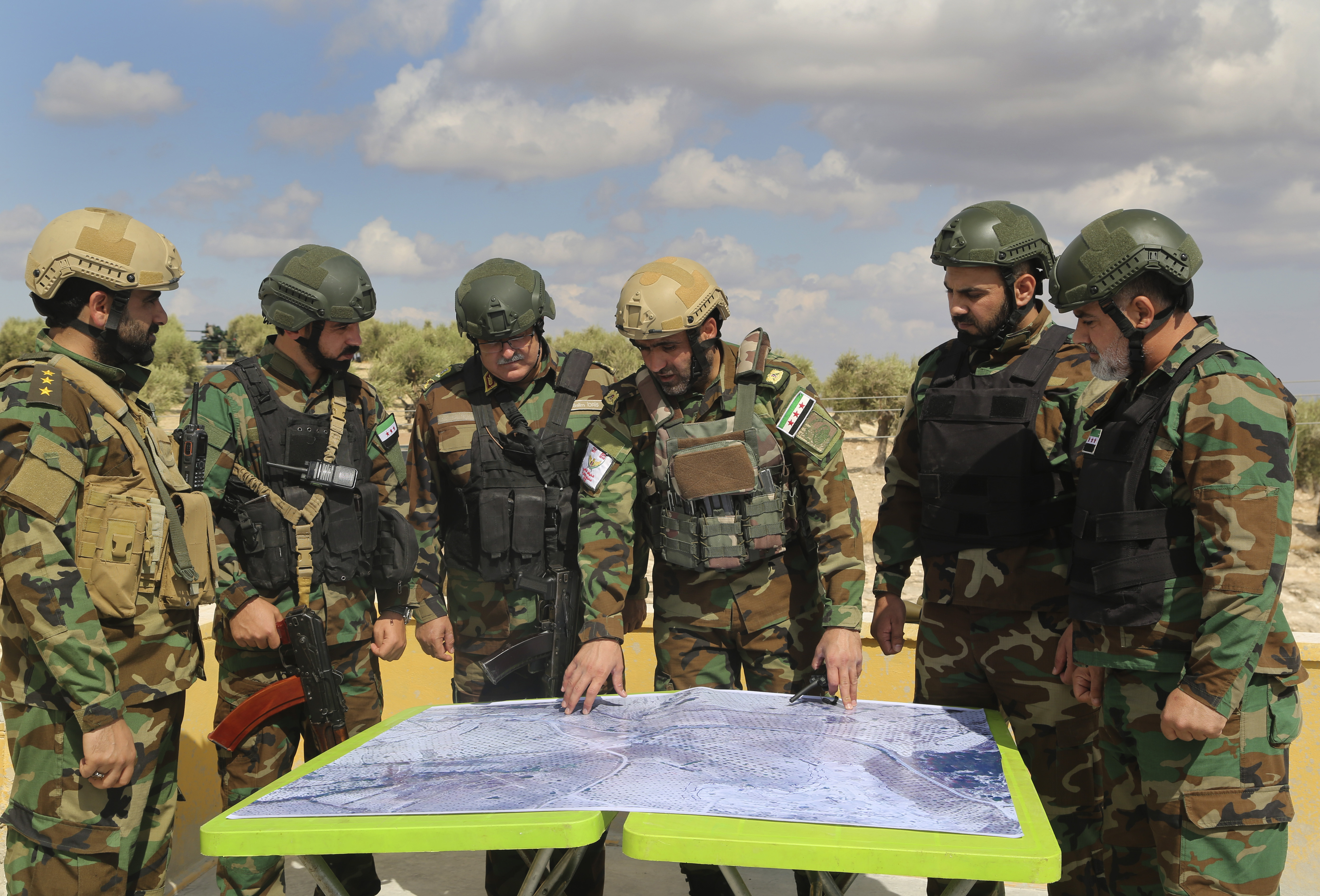 FILE - In this Monday Oct. 7, 2019 file photo, Turkish-backed forces from the Free Syrian Army look at a map during military maneuvers in preparation for a Turkish incursion targeting Syrian Kurdish fighters, near Azaz, north Syria. The Turkish trained and funded Syrian forces present themselves as heirs to the uprising against President Bashar Assad. But while they include some Islamist and former rebel factions, a large number are Arab and Turkmen fighters from northern and eastern Syria with an ax to grind against the Kurds and a reputation for violence and looting. (AP Photo, File)