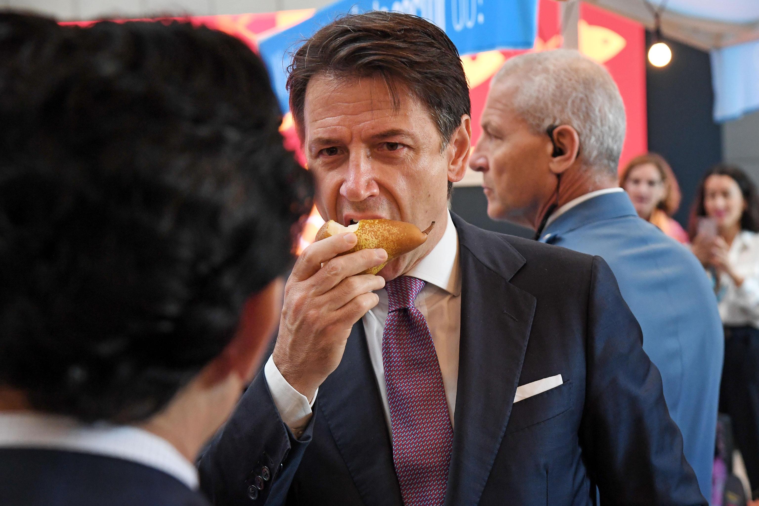 Italian Premier Giuseppe Conte (R) eats a pear as he talks with FAO Director General Qu Dongyu (L), during the visit the market of 