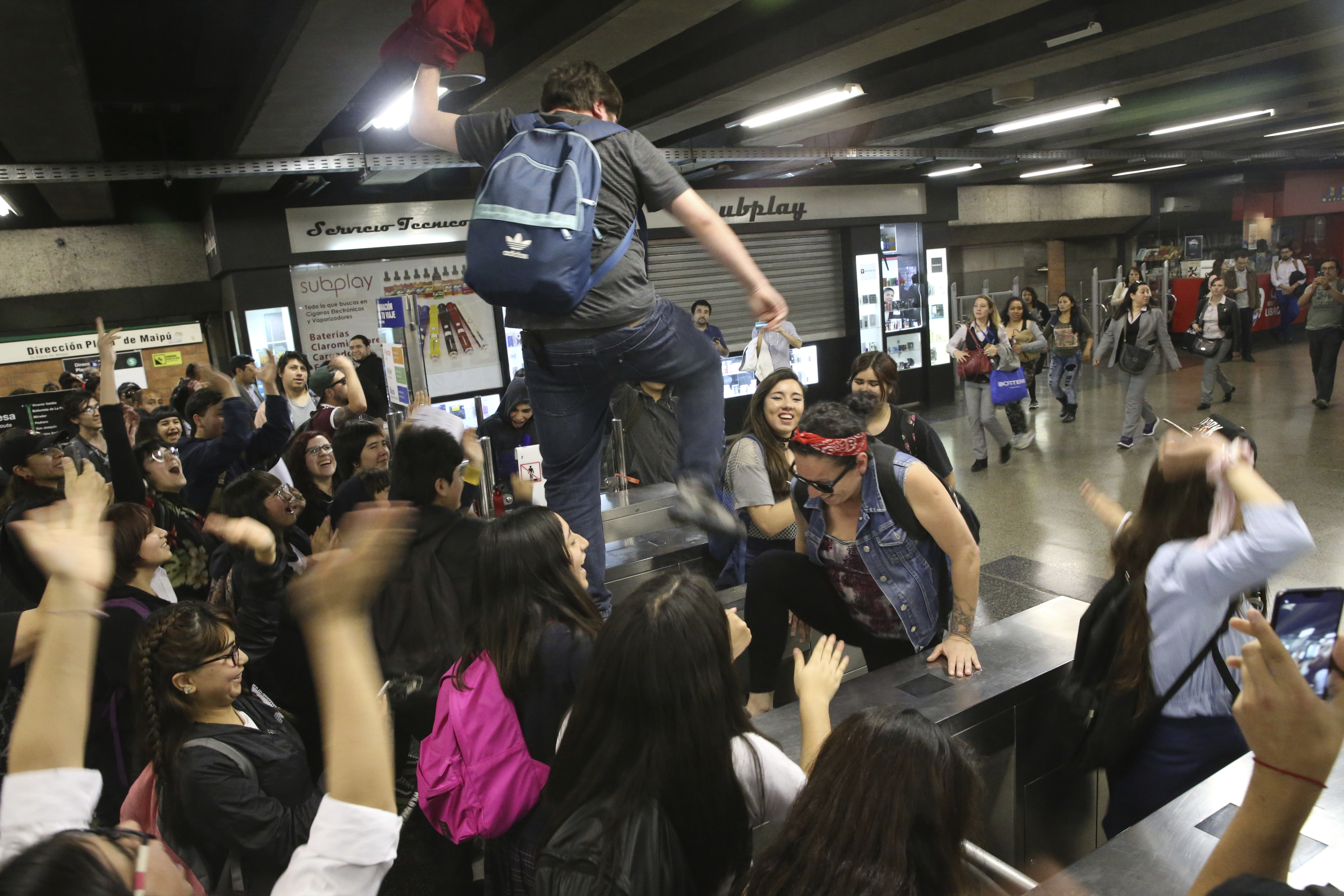 Students block the turnstile to the subway during a protest against the rising cost of subway and bus fare, in Santiago, Friday, Oct. 18, 2019. (AP Photo/Esteban Felix)