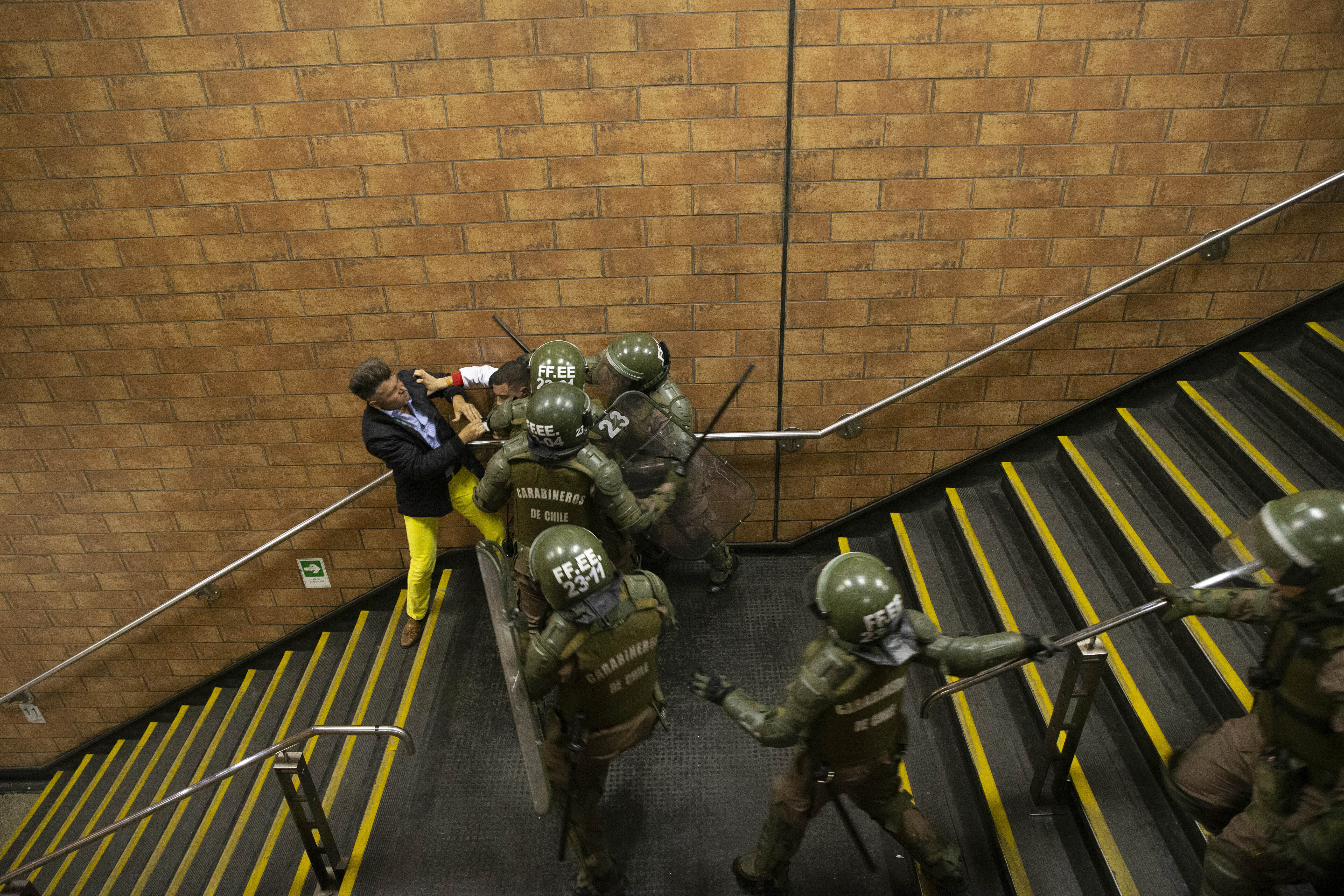 Chilean Carabineros separate two men who were fighting during a student protest against the rising cost of subway and bus fare, in Santiago, Friday, Oct. 18, 2019. (AP Photo/Esteban Felix)