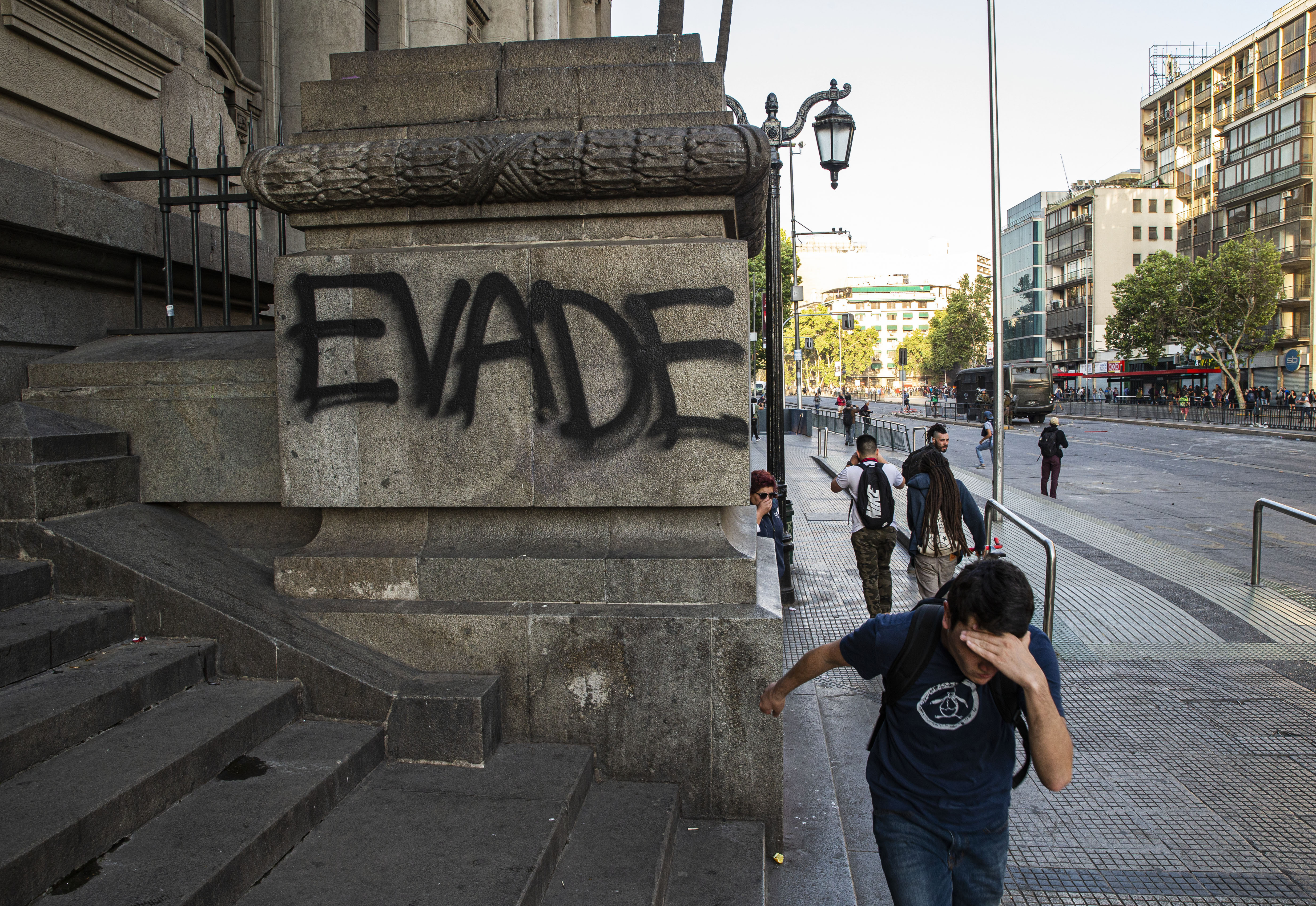 A protester runs in front a column spray painted with he Spanish word for 